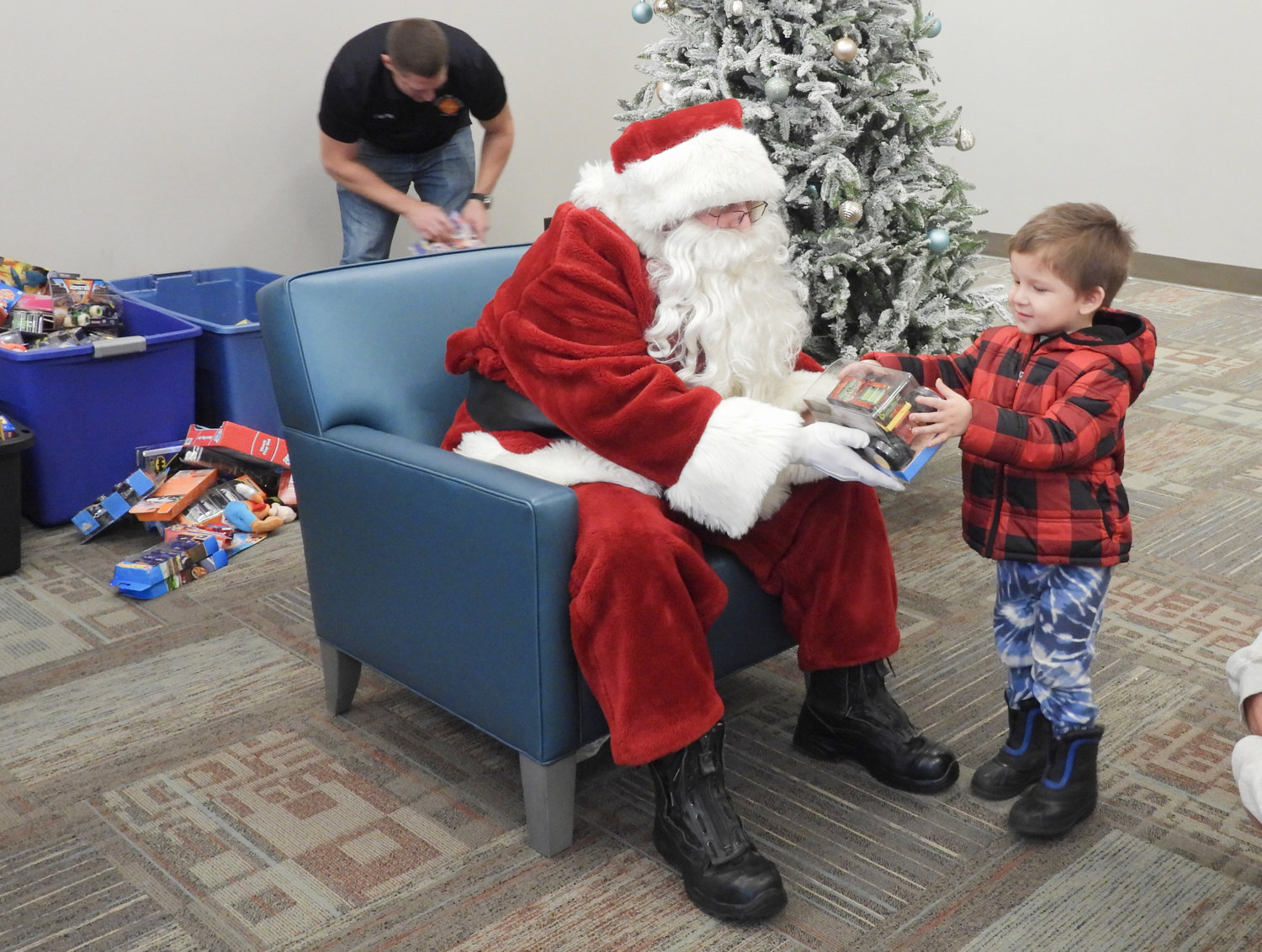 The Oneida Fire Department brings a little Christmas cheer to area children with the help of Santa Claus, listening to their Christmas wishes and giving them a toy and some treats to take home on Saturday, Dec. 3. Pictured is three-year-old Chance Thomas of Oneida, happily receiving a gift from Santa Claus.