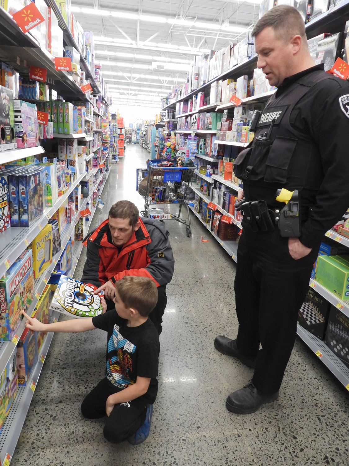 Seth Wheeler Jr., of Cazenovia, shops with his father Seth Wheeler Sr. and Deputy Sheriff Steve Markle during the Madison County Shop with a Sheriff event on Saturday, Dec. 3