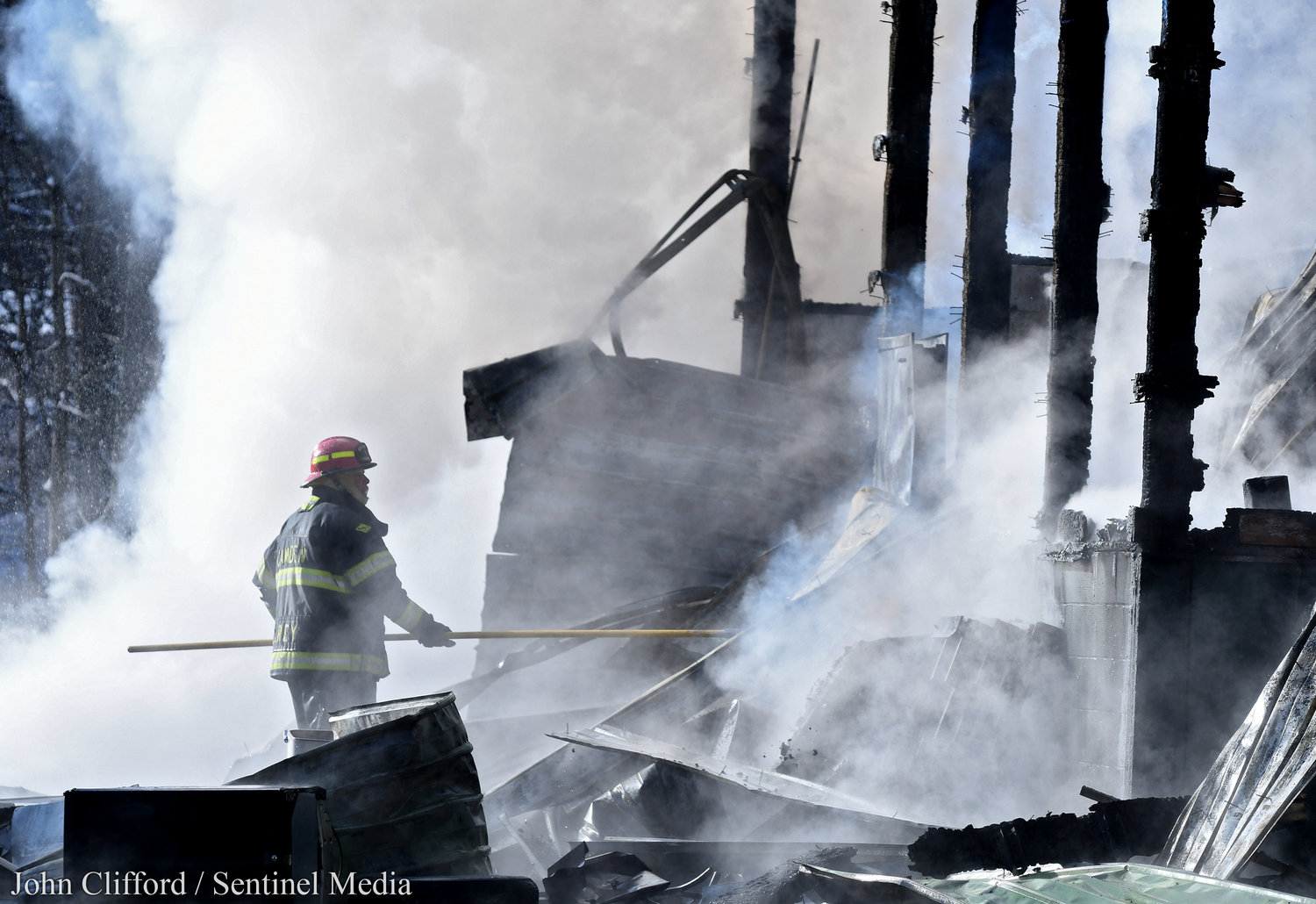 A Camden fireman uses a pike pole to remove debris so water can get to flames. Area firefighters worked a fire at the Village of Camden Department of Public Works building. The building and its contents were an apparent total loss Tuesday, Dec. 13, 2022.