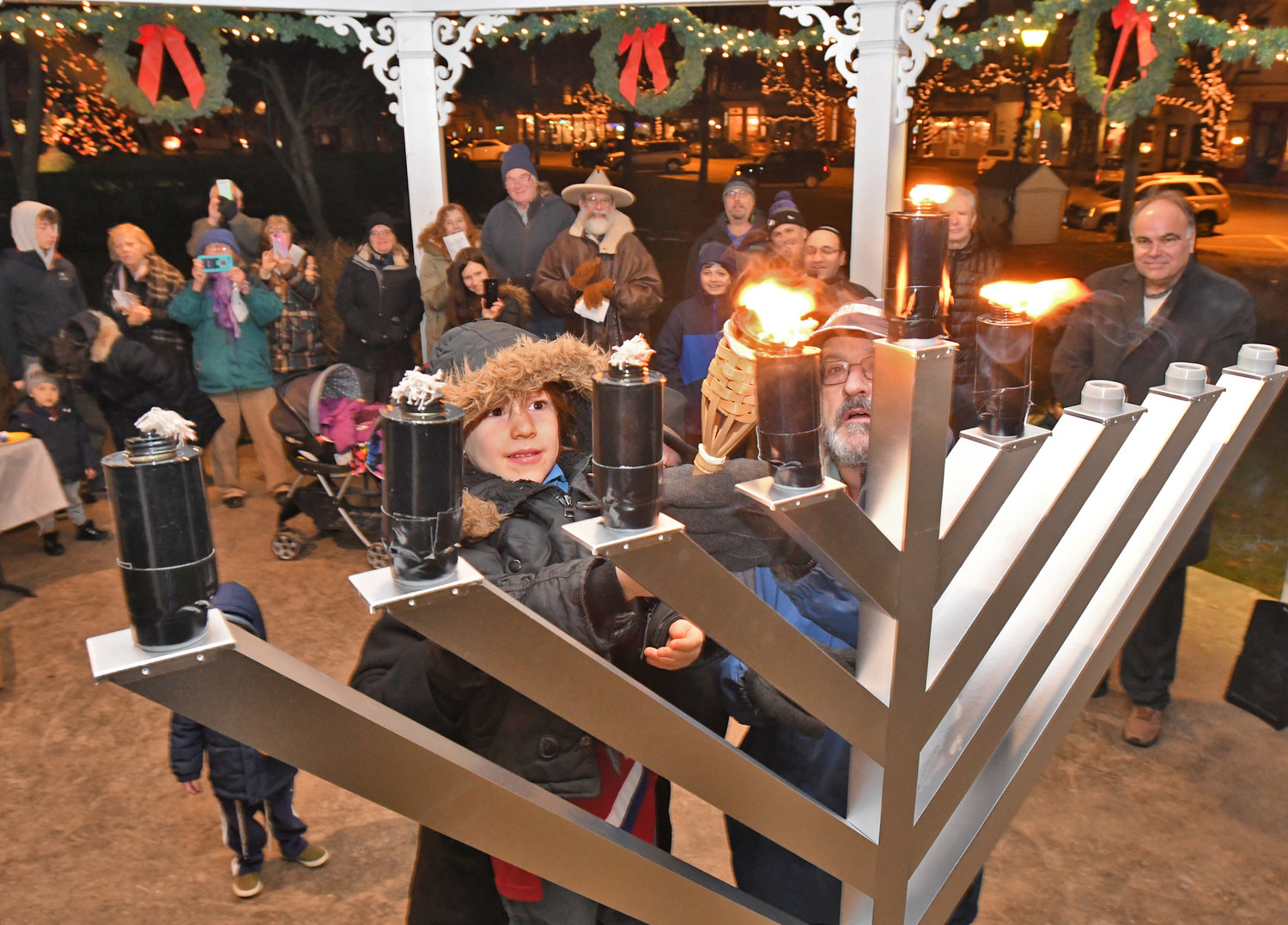 Leor Grysmintz, 4, gets help form Steven Marcus to light one of the candles of the menorah in the gazebo in Clinton in this file photo.