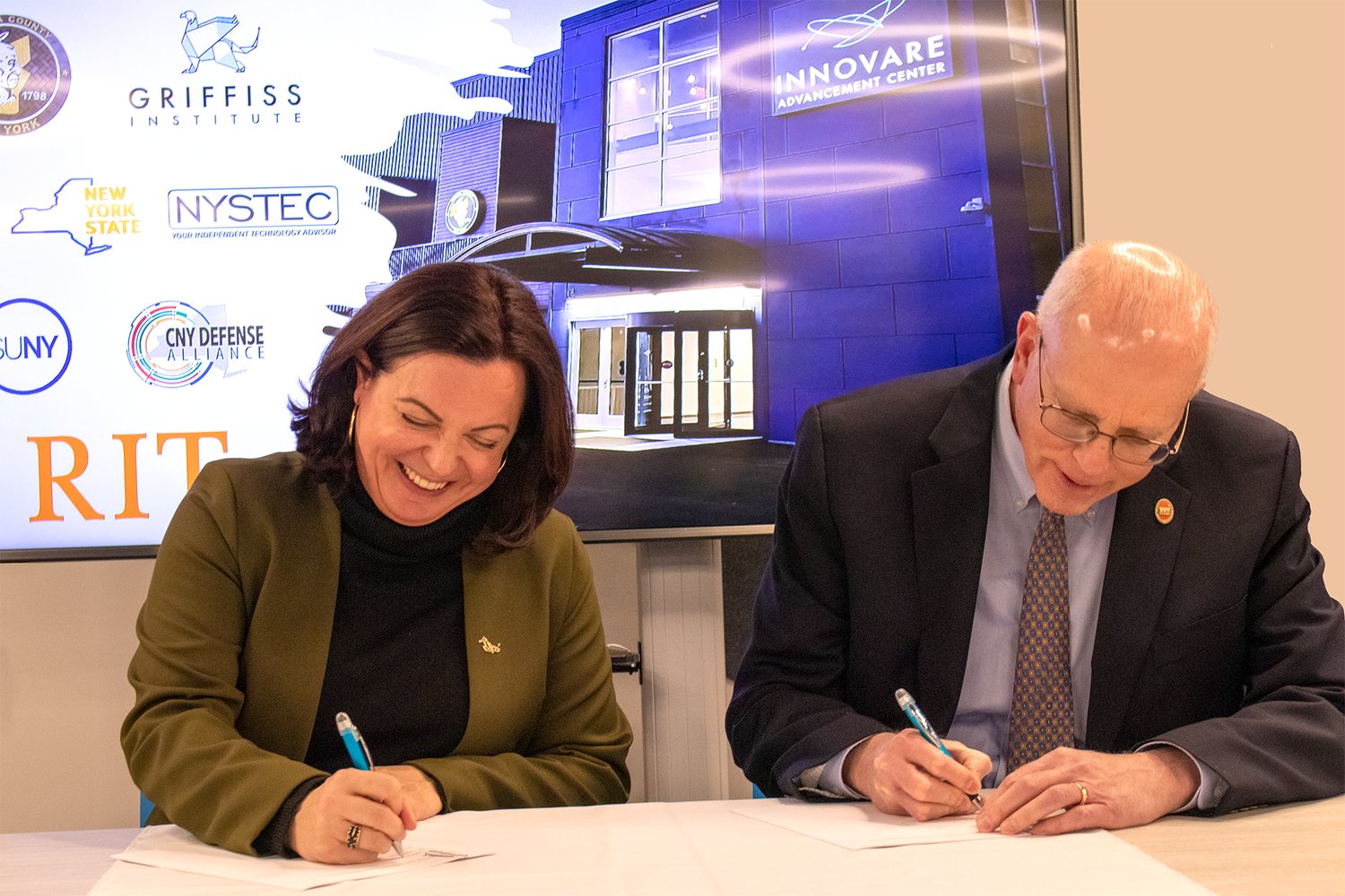 Heather Hage, president &amp; CEO of Griffiss Institute and David C. Munson Jr., president of the Rochester Institute of Technology, sign a memorandum of understanding at the Innovare Advancement Center on Tuesday.