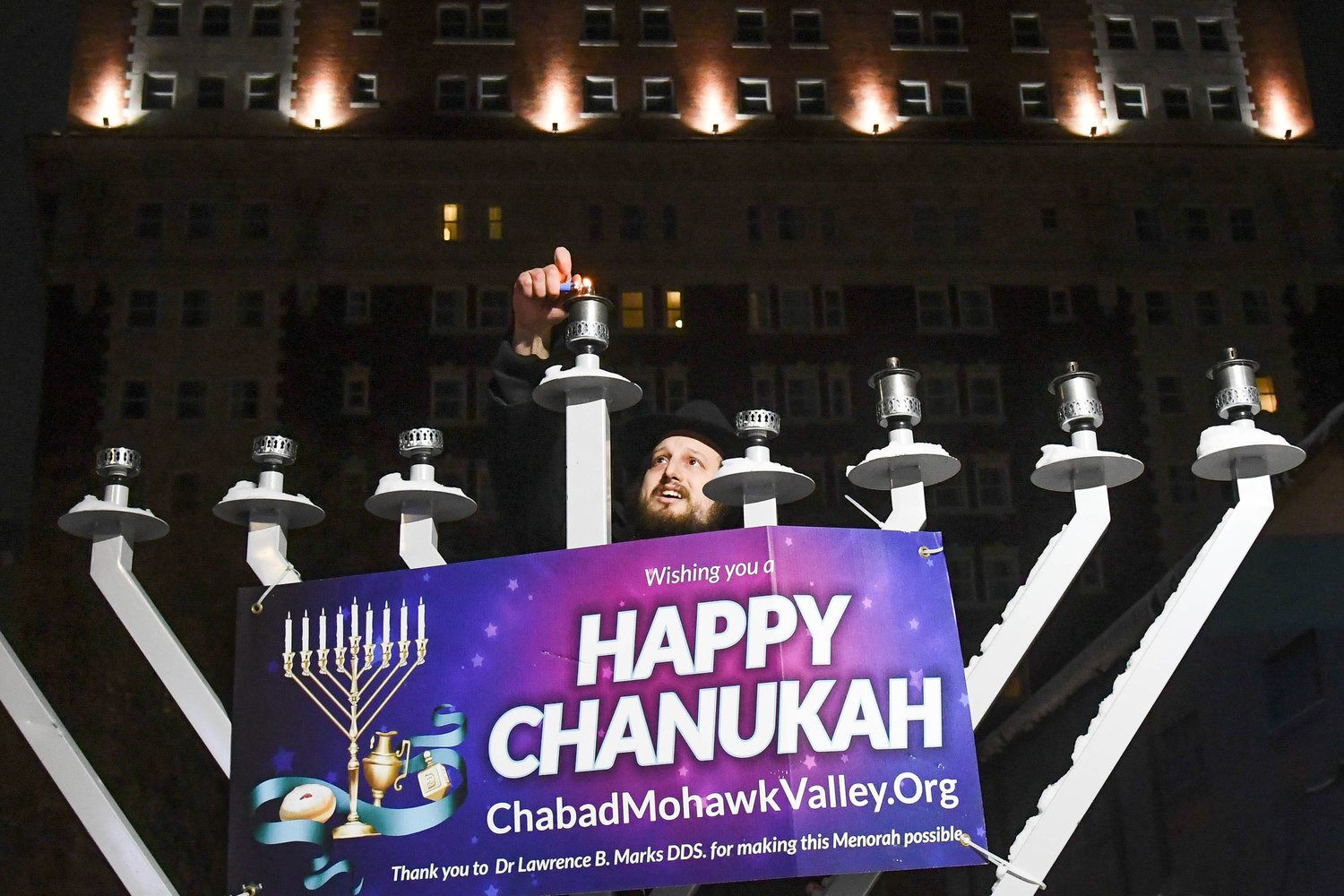 Rabbi Levi Yitzchok Charitonow, from the Chabad of the Mohawk Valley, lights the shammash on a large menorah outside of Liberty Bell Park in celebration of Hanukkah on Tuesday, Dec. 20 in Utica.
