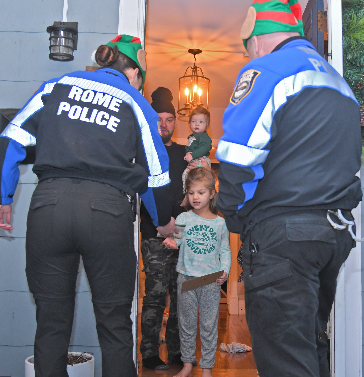 Rome Police officers Jenna Kiskiel and Anthony Calandra deliver a letter from the North Pole and some reindeer food to 5-year-old Teagan Thomson in Rome on Tuesday. With Thomson is her father, Jeremy Thomson. Teagan was one of dozens of children who dropped off their letters to Santa in the special mailbox the Rome Police set up at the station this year.