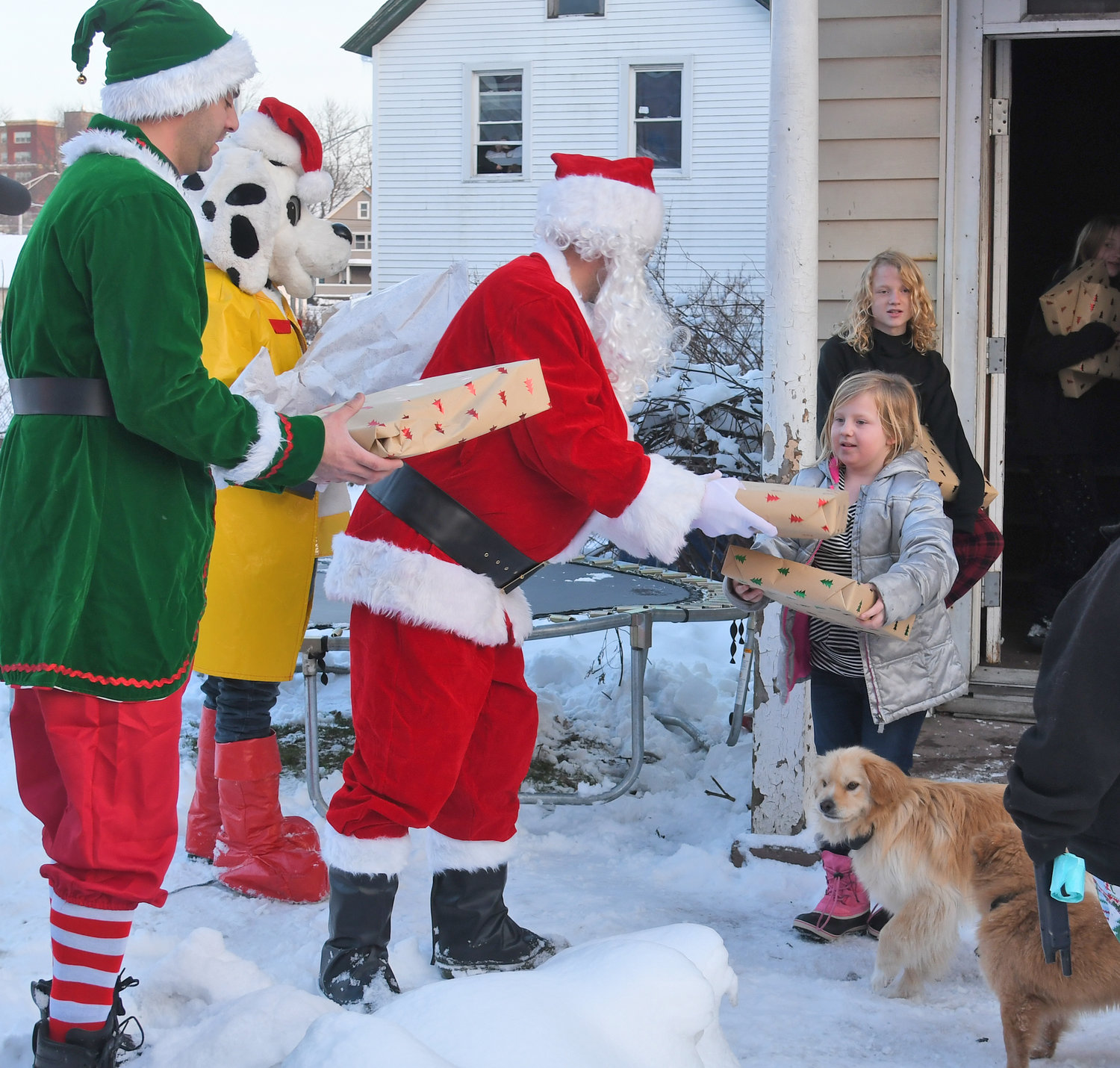 Santa Claus and one of his elves joined Sparky the Fire Dog to hand out presents to Taya Euson, age 9, and her brother, Matthew, age 13, at their home in Rome on Wednesday. The Rome Fire Department has been handing out gifts to underprivileged children in the city for years.