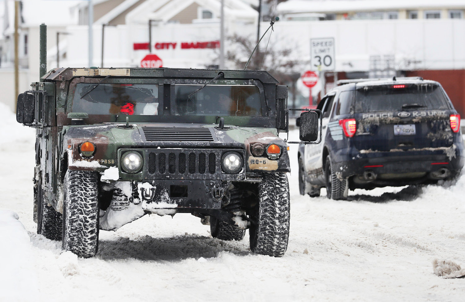 A National Guard truck drives past a police cruiser on a snowy street in Buffalo on Tuesday, Dec. 27. The National Guard is in Buffalo to help with clean up after a blizzard hit four Western New York counties.