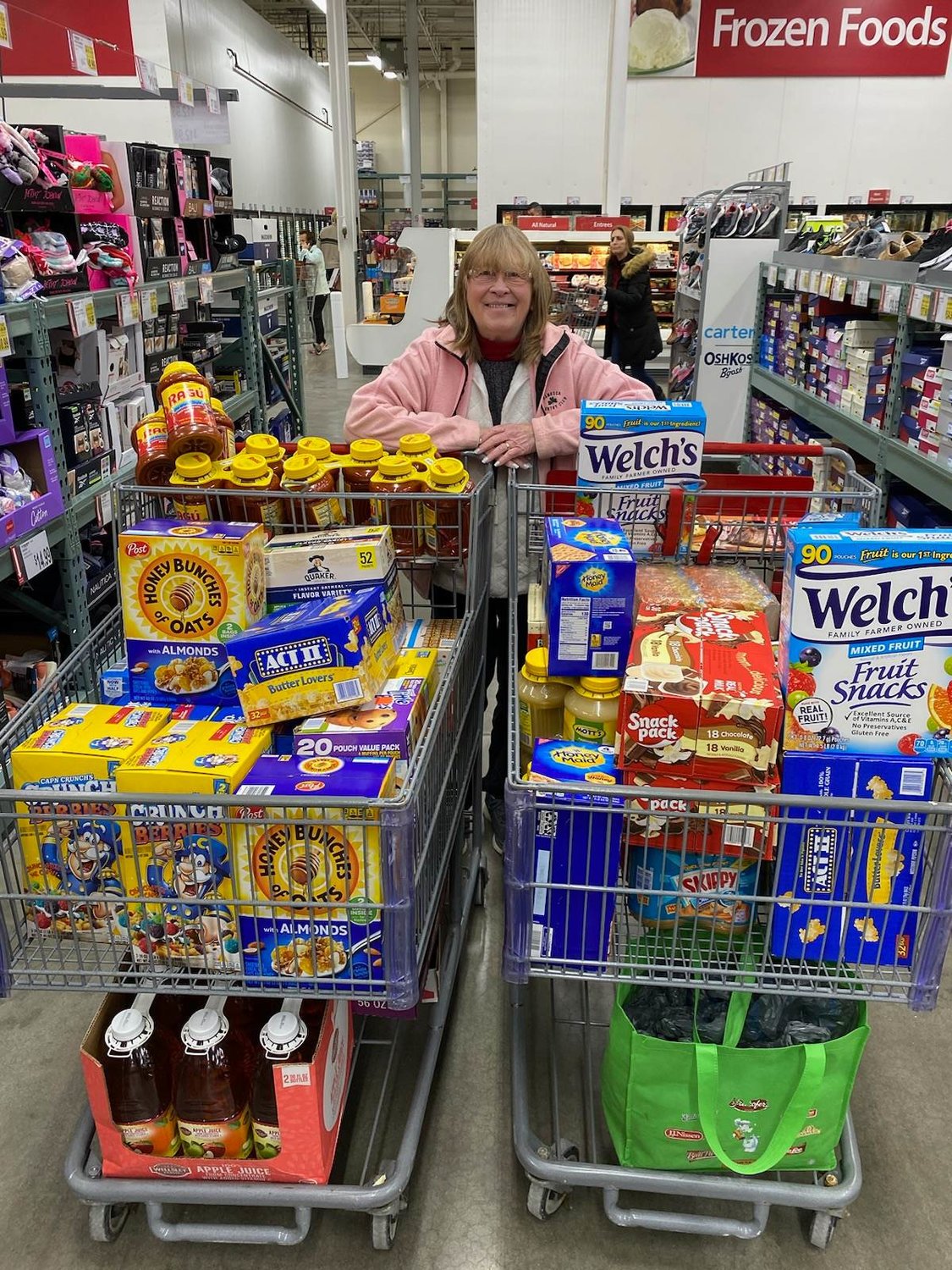 Oneida American Legion Auxiliary Vice President Sue Fid poses with two carts of food items of their recent Fill Um Up Project.