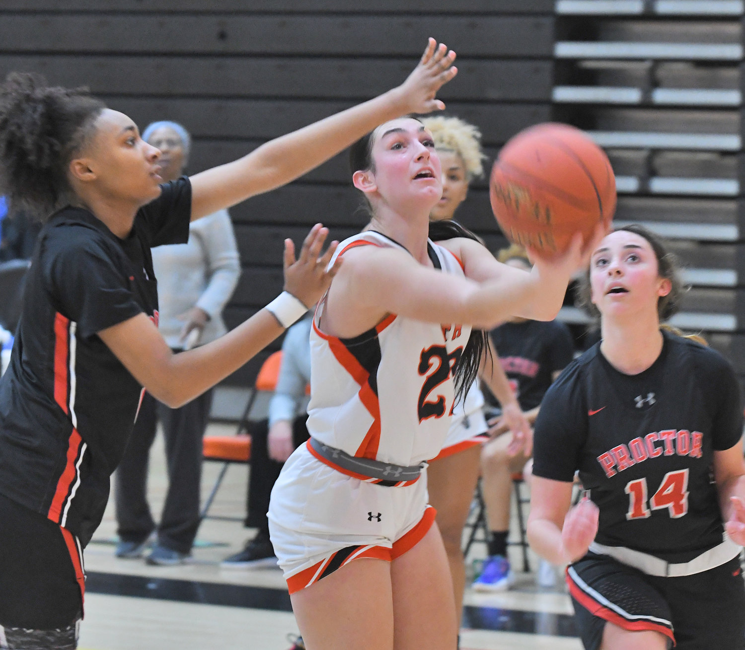 Rome Free Academy's Mia Mirabelli scoops the ball under the arm of Proctor's Armanie Gordon, left, to score a basket in the first quarter at RFA Saturday. At right is Proctor's Kaia Singleton.