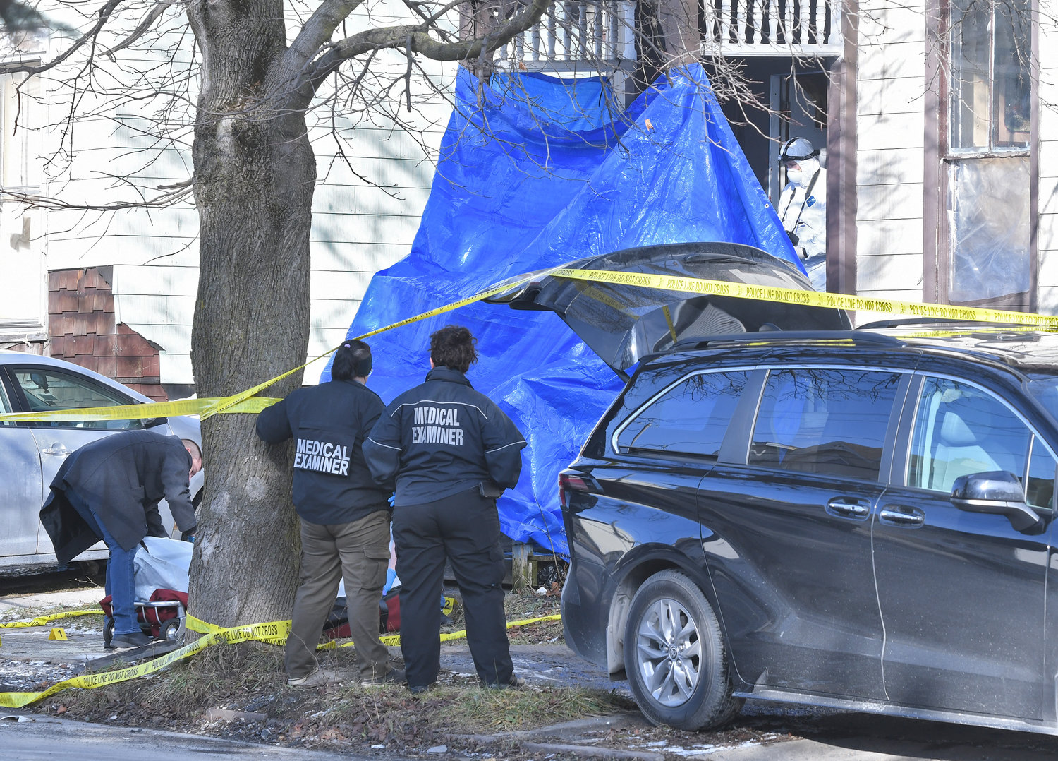 A homicide victim killed on Eagle Street in Utica on Wednesday is removed from the scene. Members of the Onondaga County Medical Examiner's Office look on after having examined the body and the scene.