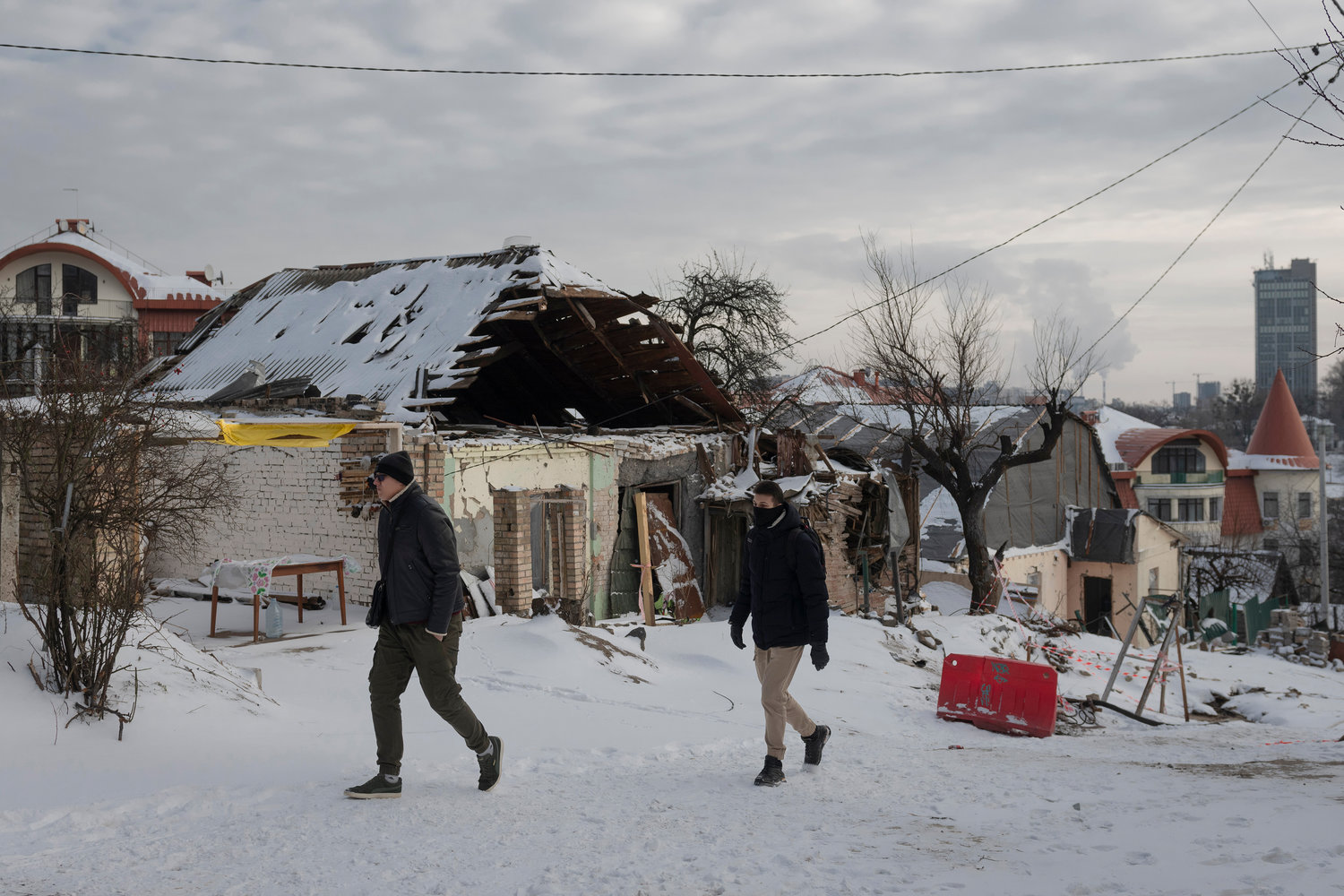 People pass by buildings impacted by Russian missile shelling, in background, in Kyiv, Ukraine, on Wednesday, Jan. 11. A new area non-profit agency has moved closer to helping a Ukrainian woman and her two children, ages 3 and 6, relocate to Rome.