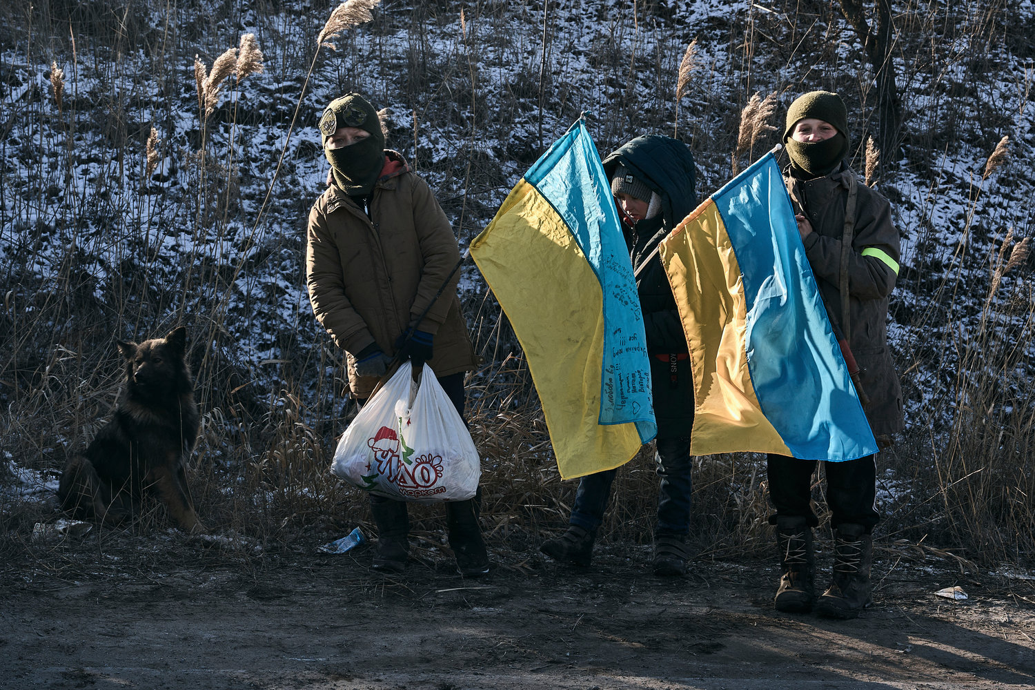 Ukrainian children hold national flags as they stand guard at an improvised checkpoint close to Sloviansk, Donetsk region, Ukraine, Wednesday, Jan. 11, 2023.