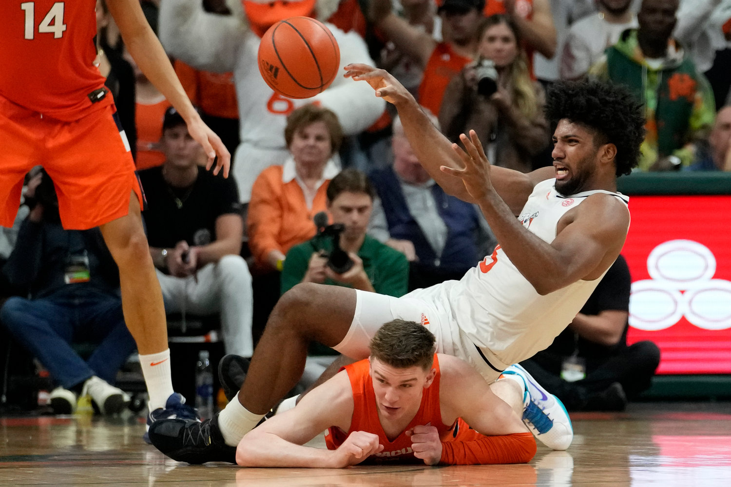 Syracuse guard Justin Taylor, bottom, falls to the court as Miami forward Norchad Omier passes the ball during the second half of Monday night's game in Coral Gables, Fla.