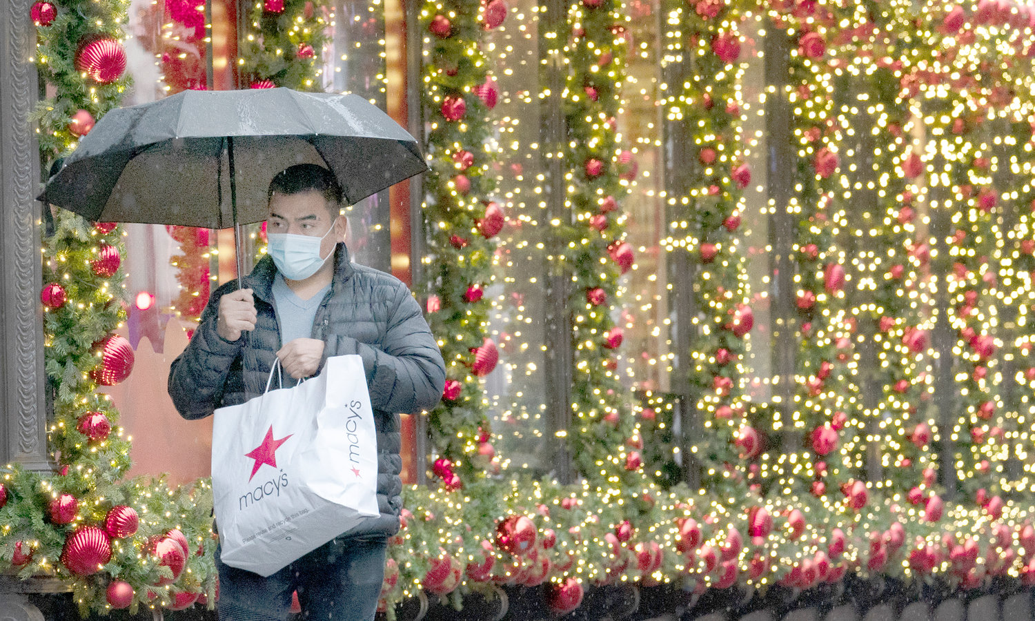 A shopper walks by a holiday window display in New York City in this file photo. Don’t wait to take care of any debt you incurred over the holidays, financial experts say.