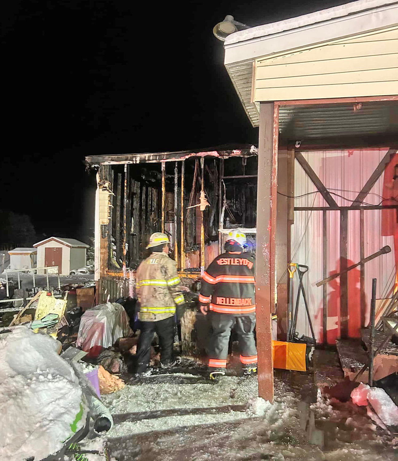 Firefighters look over what remains of a mobile home fire on Route 26 in Ava Monday evening.