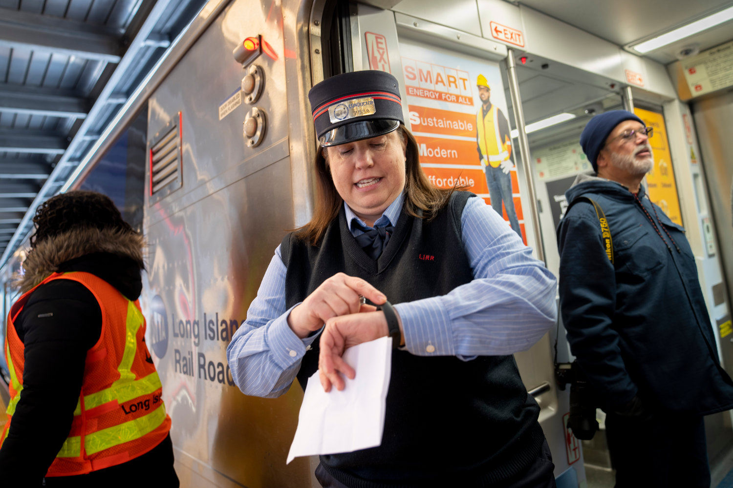 Kelly Curry, a 23-year veteran of the MTA, checks her watch as her Long Island Rail Road train departs for its inaugural trip from Jamaica station towards Manhattan, Wednesday, Jan. 25, 2023, in the Queens borough of New York. After years of delays and massive cost overruns, one of the world's most expensive railway projects has begun shuttling its first passengers between Long Island to the latest addition to New York City's iconic Grand Central Terminal. (AP Photo/John Minchillo)