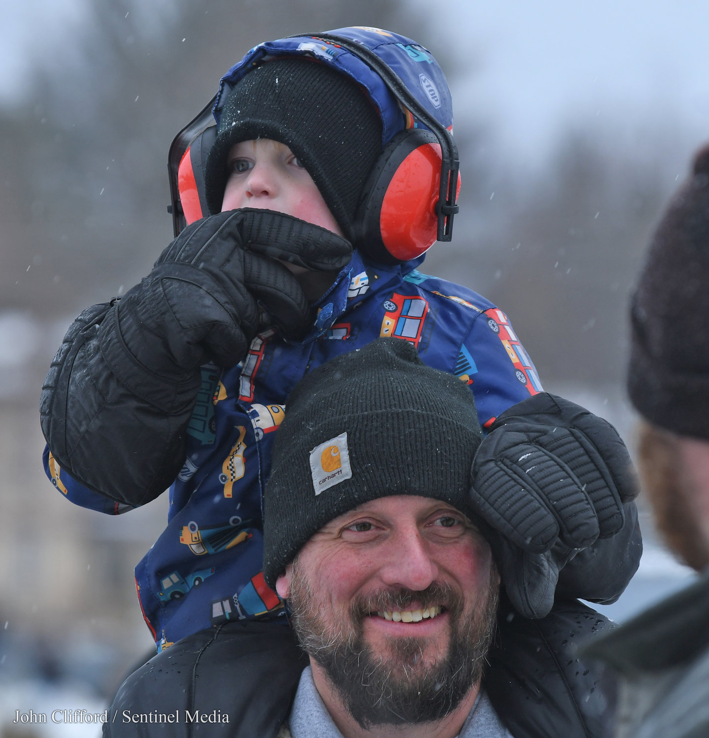 Brad Knab and his grandson Luke Woodring on his shoulders enjoy the Boonville  Snow Festival racing actioin Sunday afternoon at Boonville Fairgrounds.