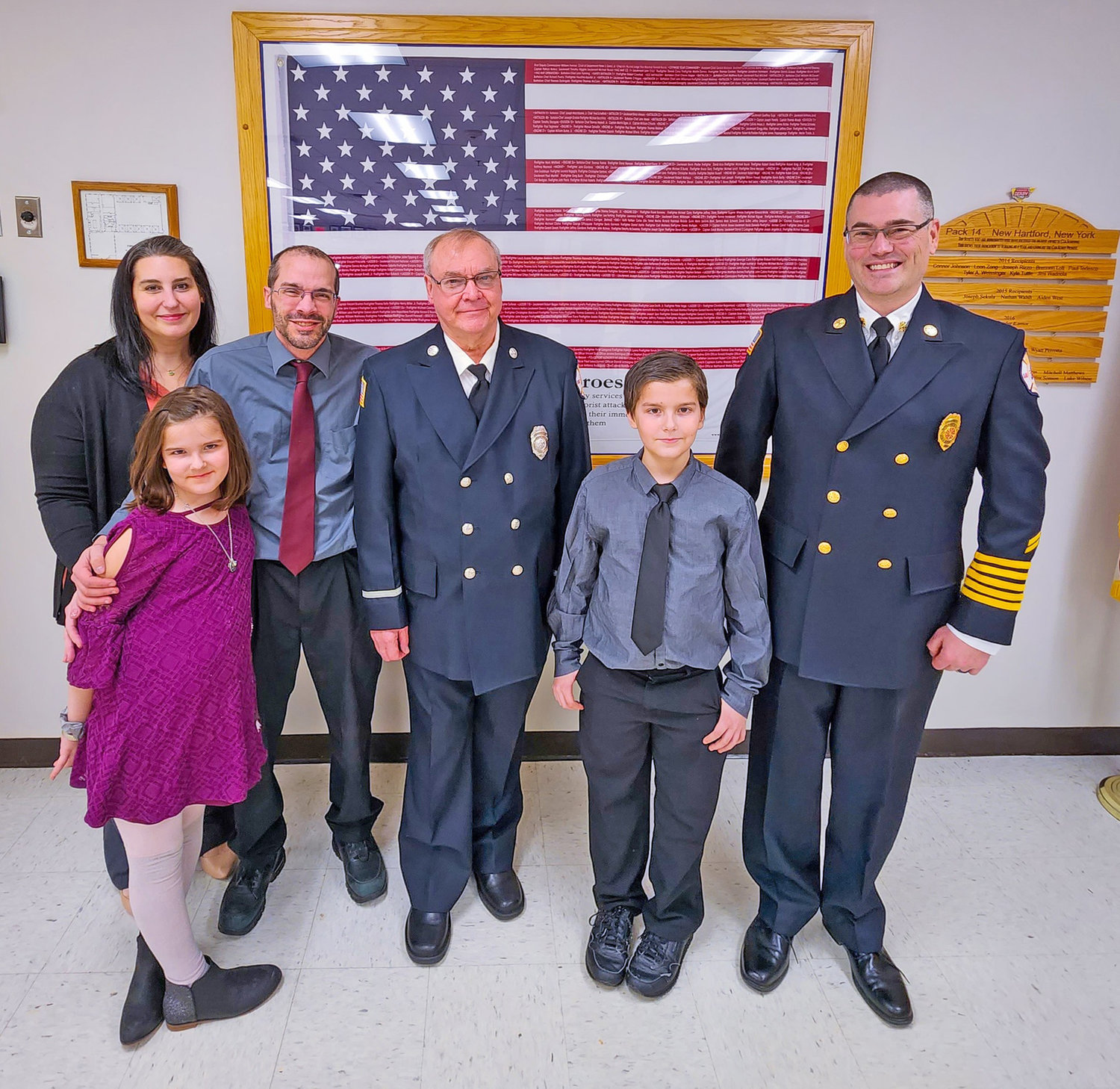 Carter Carro, age 11, stands with Willowvale Fire Chief Noel Ames, right, and his family at the department’s monthly meeting Thursday night. He was honored by the department for his heroic actions in saving a neighbor’s home from a garage fire.