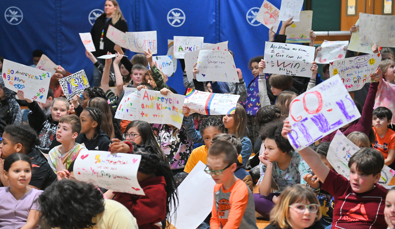 Gansevoort Elementary School students hold up signs Friday, Feb. 10 as their classmates complete math problems during the Math Fact Super Bowl STEM finals.