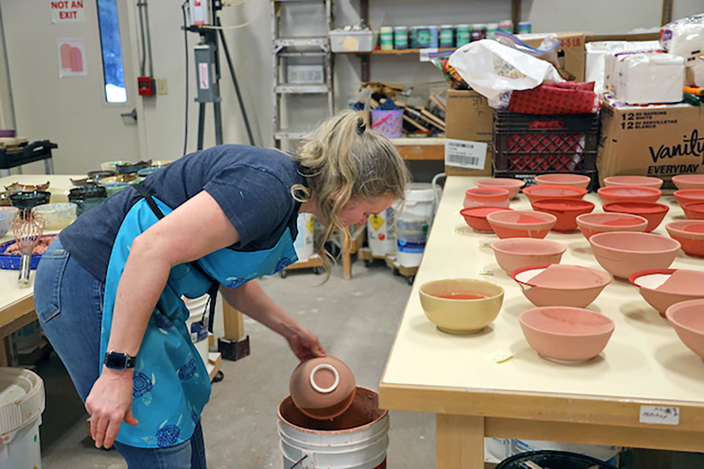 View instructor Kristin Martin dips a bowl in glaze as she gets her pottery ready for the upcoming Chili Bowl Luncheon.