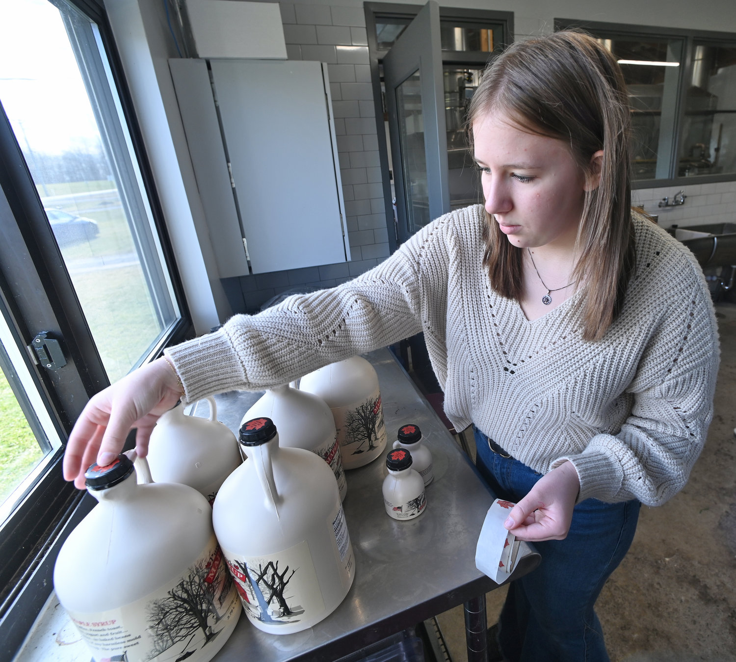 Stockbridge Valley Central School junior Madison Nolley puts stickers on jugs of maple syrup produced by the Stockbridge Valley FFA Wednesday, Feb. 15 in their sap house in Munnsville.