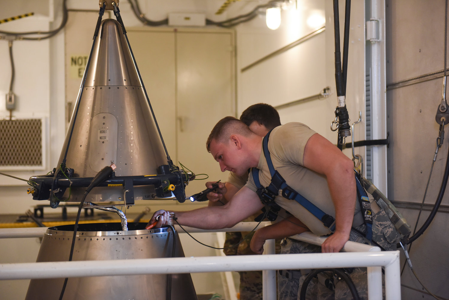 In this image provided by the U.S. Air Force, Senior Airmen Andrew Whitener and Tyler Glodgett 341st Missile Maintenance Squadron topsiders, inspect the cable connections of an intercontinental ballistic missile during a Simulated Electronic Launch-Minuteman test Sept. 22, 2020, at a launch facility near Great Falls, Mont.
