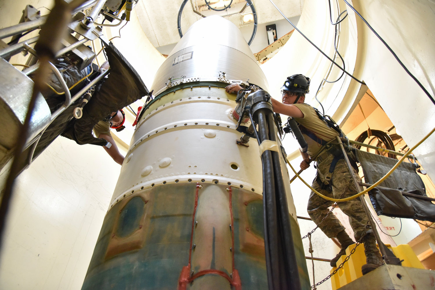 In this image provided by the U.S. Air Force, Airman 1st Class Jackson Ligon, left, and Senior Airman Jonathan Marinaccio, 341st Missile Maintenance Squadron technicians, connect a re-entry system to a spacer on an intercontinental ballistic missile during a Simulated Electronic Launch-Minuteman test Sept. 22, 2020, at a launch facility near Malmstrom Air Force Base in Great Falls, Mont. The top Air Force officer in charge of the nation's air and ground-launched nuclear missiles has requested an official investigation into the number of officers who are reporting the same type of blood cancer after serving at Malmstrom Air Force Base. (Senior Airman Daniel Brosam/U.S. Air Force via AP)
