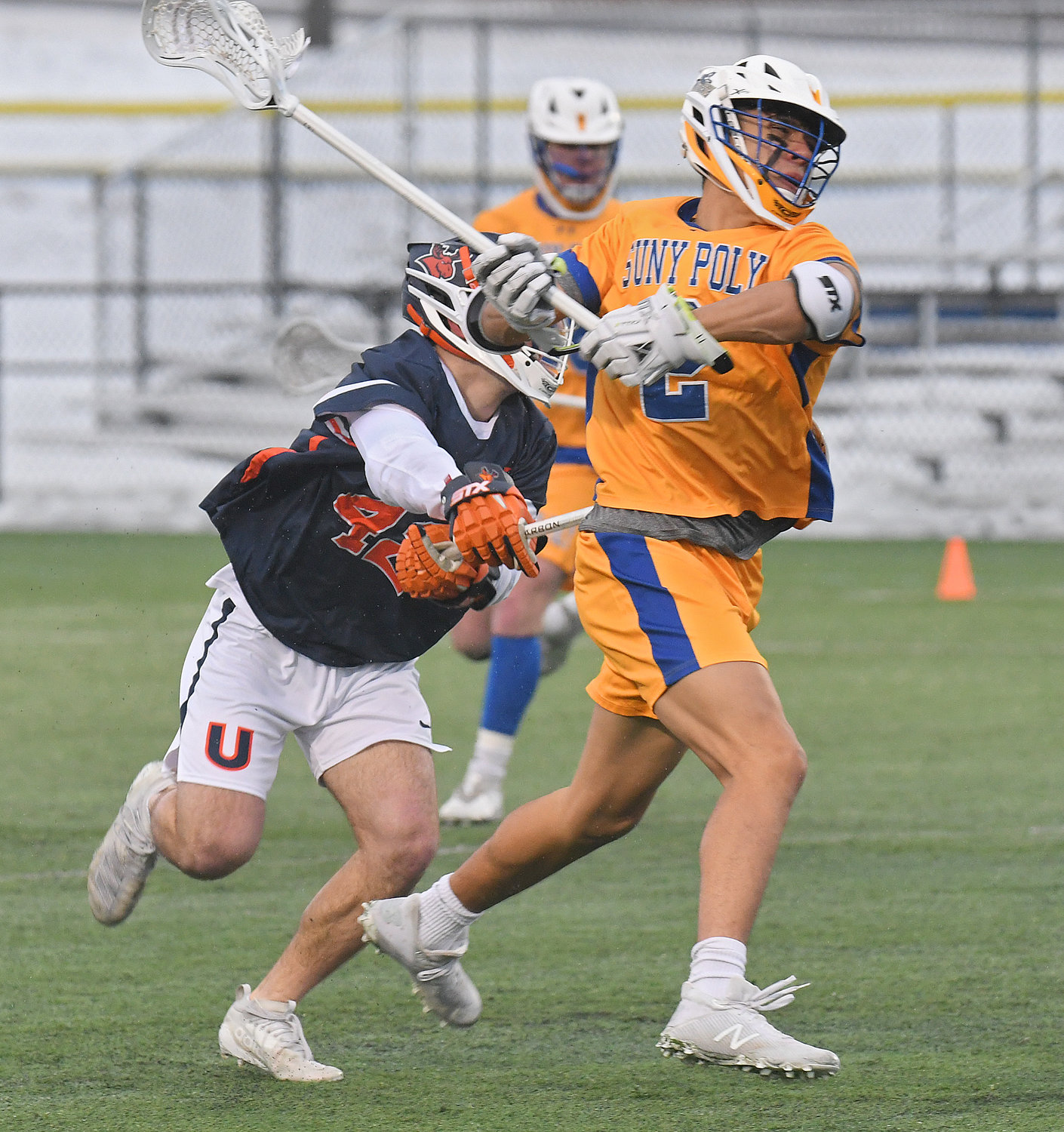 WINDING UP — SUNY Poly's Luke Taylor winds up for a shot with Utica University's Michael Mecca trailing in the first quarter of Thursday afternoon's men's lacrosse game at SUNY Poly. The Pioneers won 4-1.
