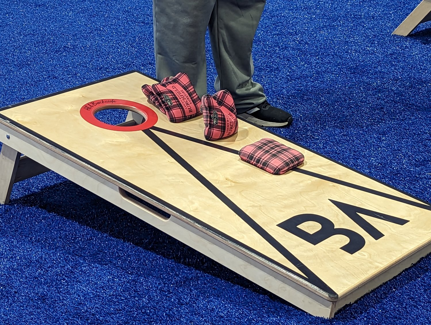 A standard cornhole board. Players attempt to toss bean bags into the hole for three points, with one point awarded for managing to stay on the sloped, slippery board.