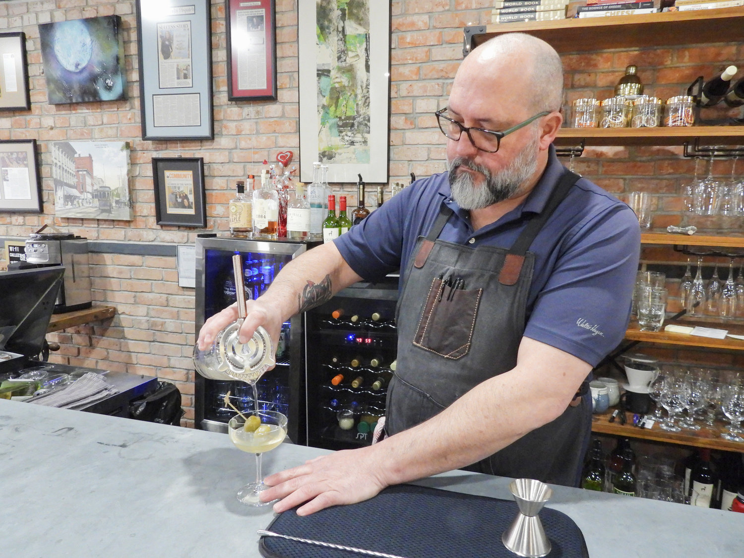 Casey Baney, co-owner of Callee 1945, finishes up a dirty martini and pours it into a waiting glass â complete with olive garni