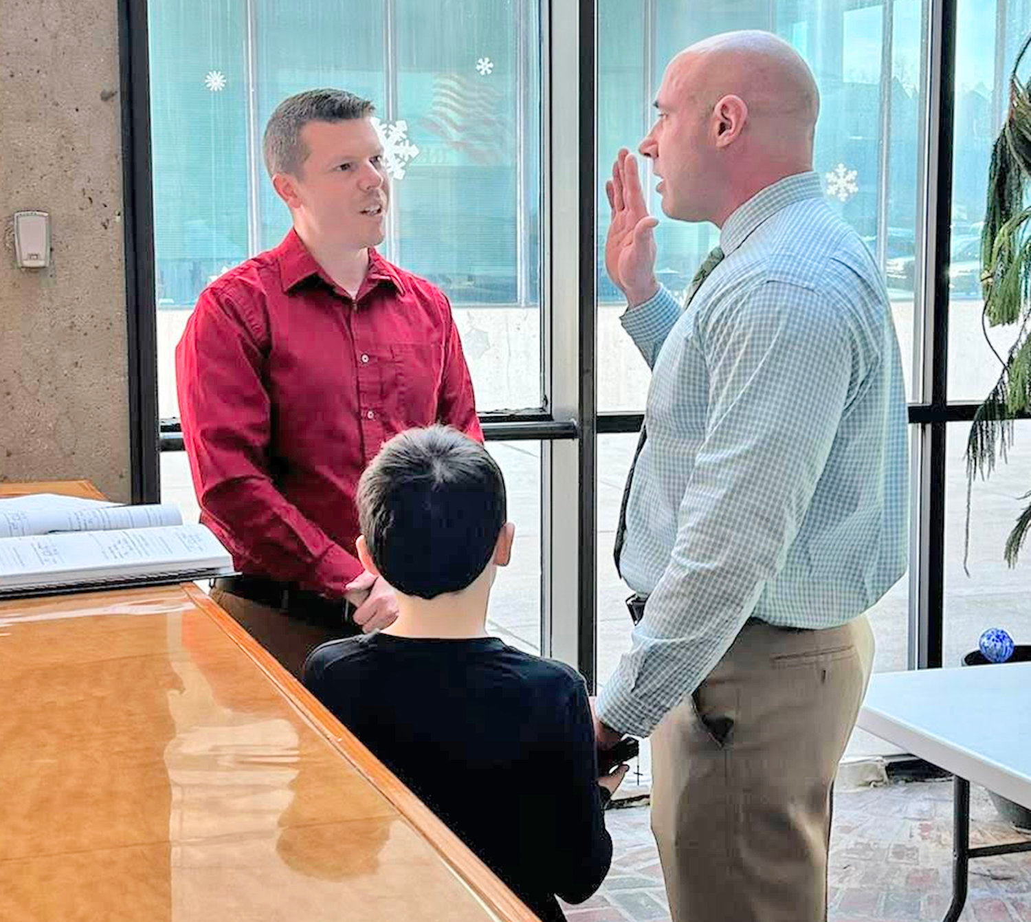 Rome Police Officer Michael Uhl is sworn into service as his son holds the Bible on Friday, by Rome City Clerk Eric Seeley. Uhl is rejoining the department after serving a stint with the Town of Webb Police Department in Herkimer County.