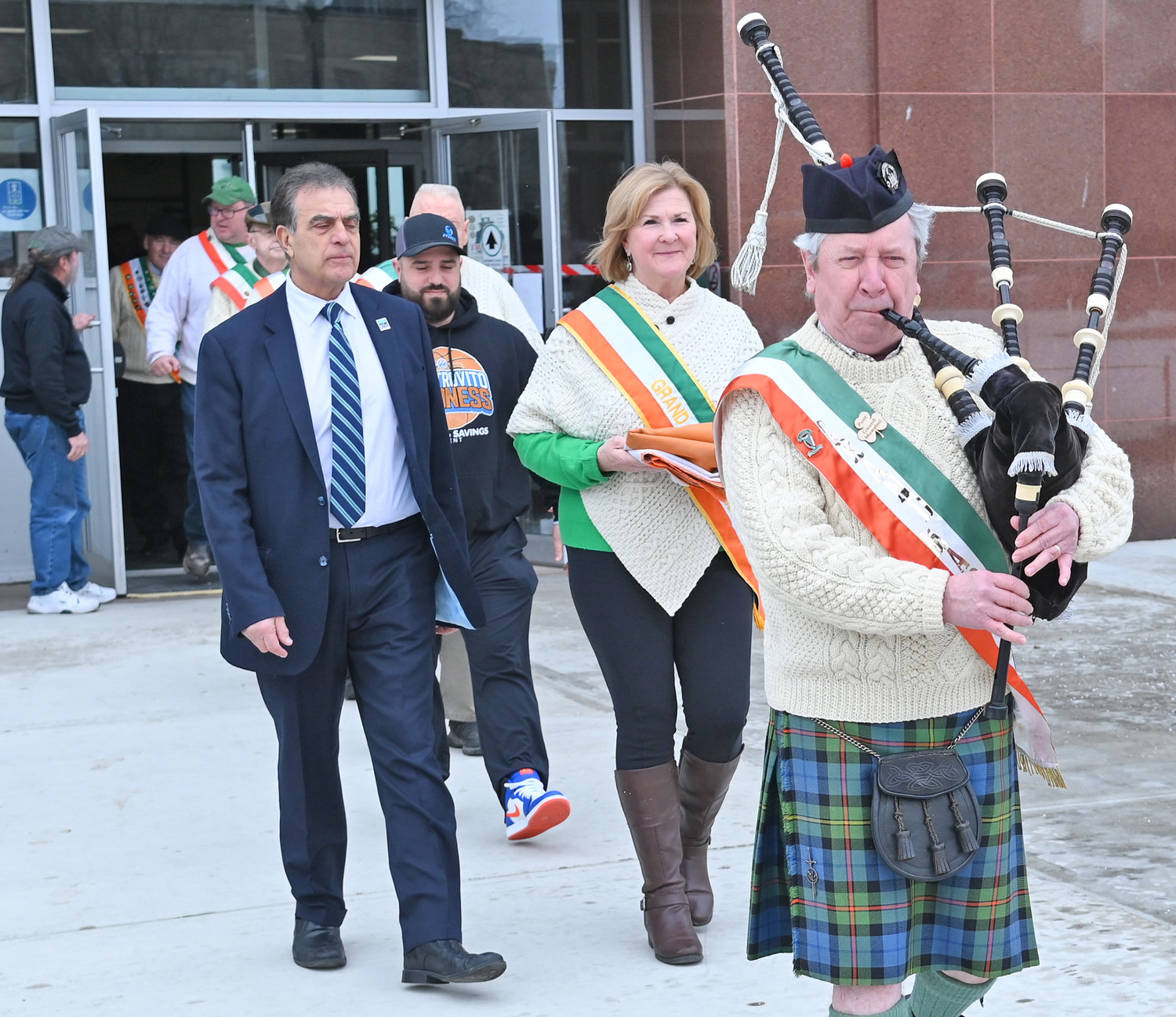 LEADING THE WAY — Bagpiper Dr. Daniel Murphy leads Mayor Robert Palmieri and Colleen Kain Martin, the grand marshal of the upcoming St. Patrick’s Day Parade in Utica, as they head out of Utica City Hall and toward’s the flag pole as they prepare to hoist the Irish flag on Wednesday afternoon.