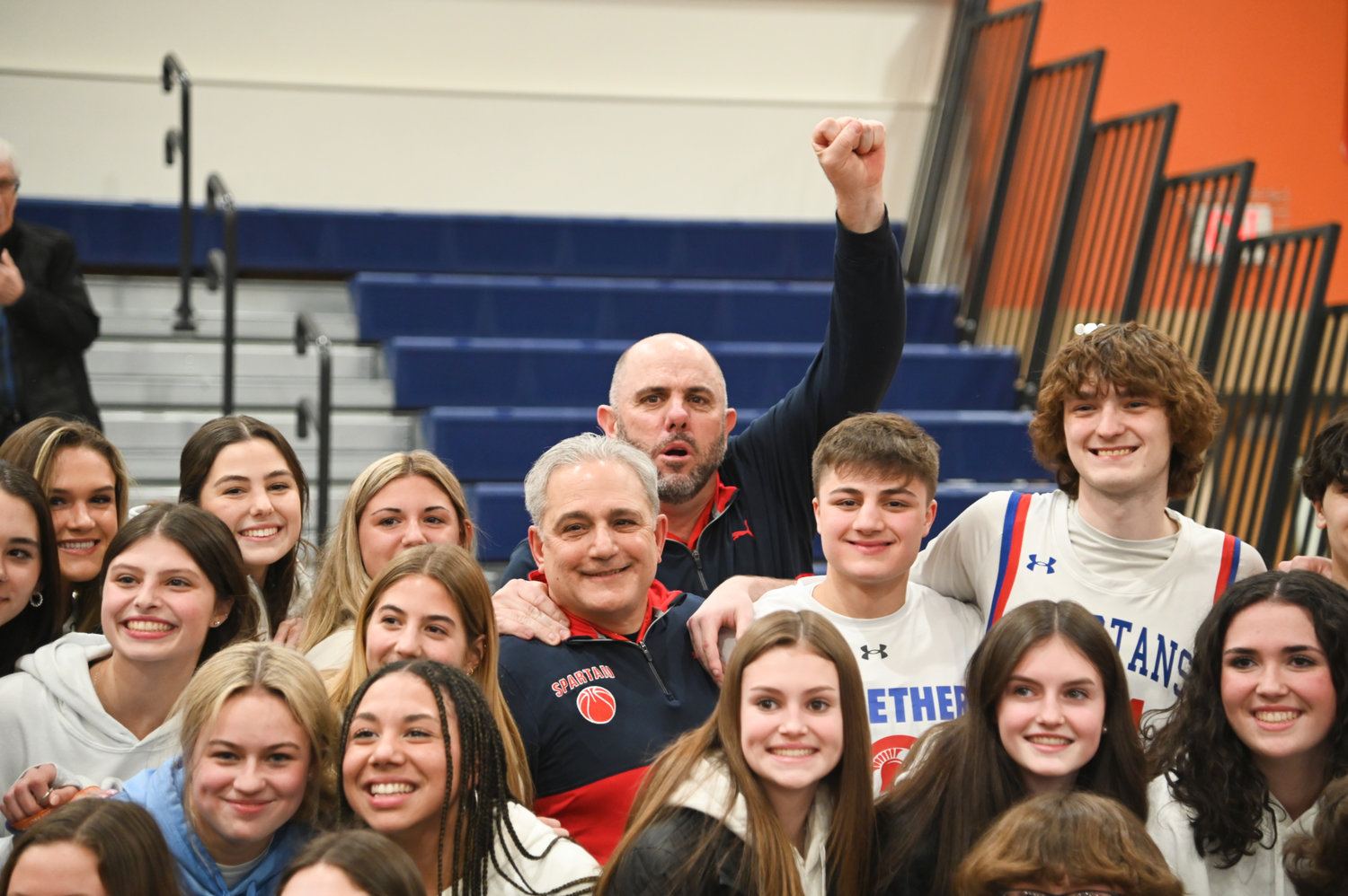 New Hartford coach John Randall (center) celebrates with his team and fans on Wednesday following the team's 69-60 win over Troy in the state Class A subregional game at Liverpool High School. It is the second time in as many seasons Randall has helped guide the Spartans to the state tournament.