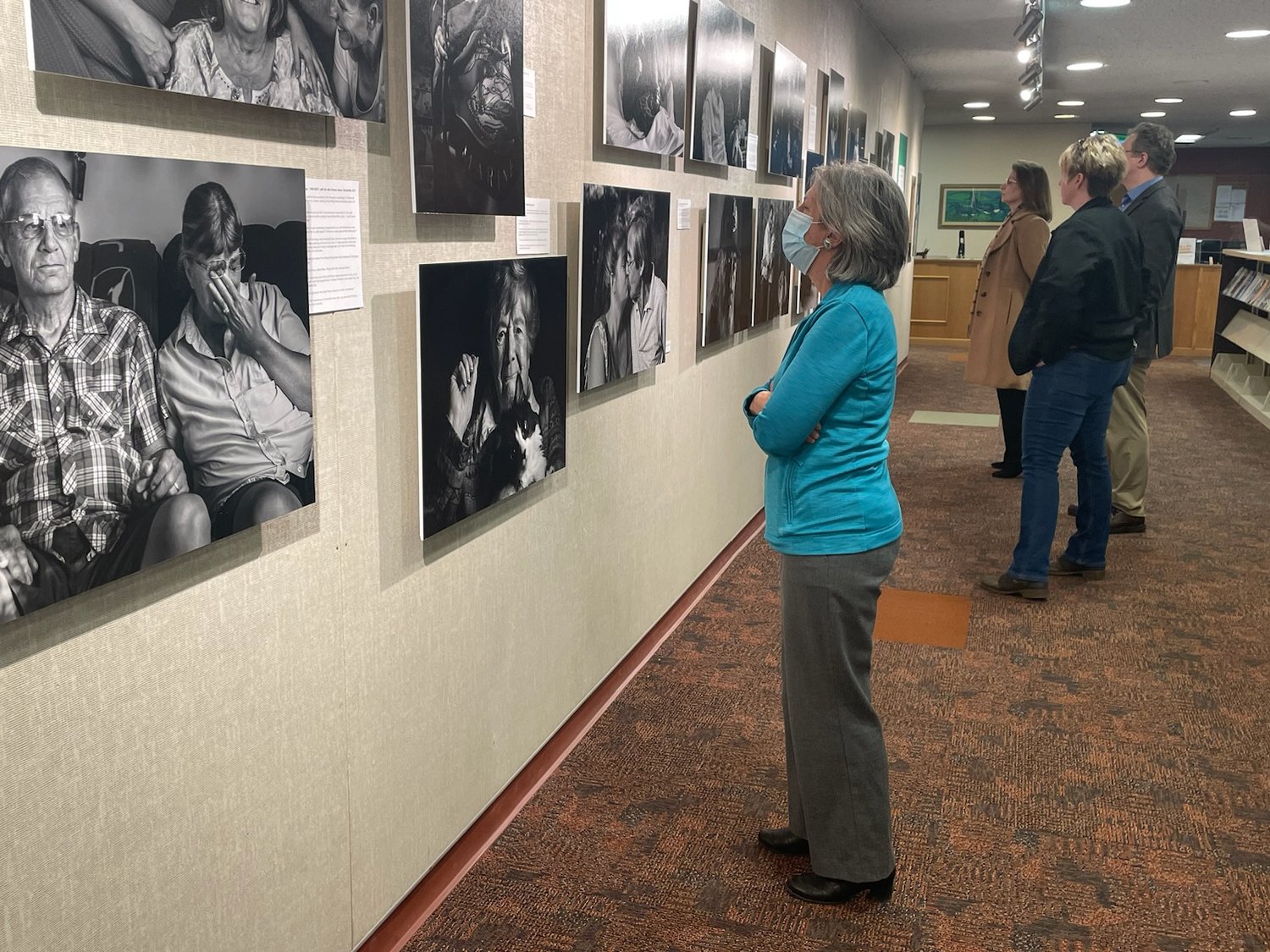 Vistors reflect on the photos and quotes of former hospice patients included in The Last Portrait exhibit open now through April 11 at SUNY Morrisville.