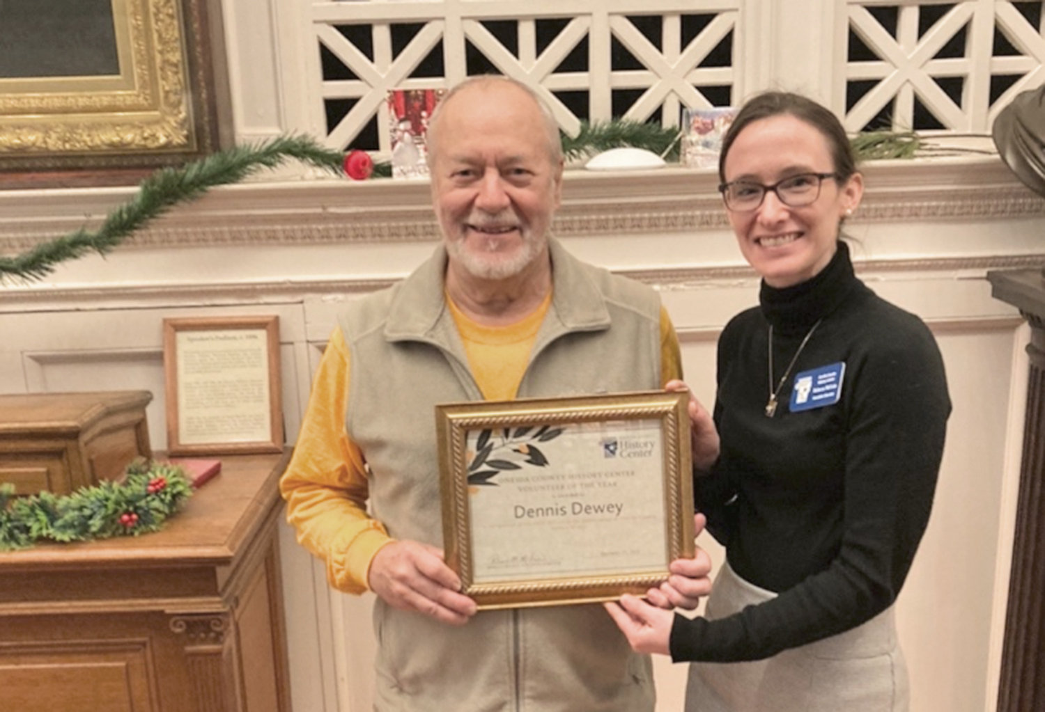 Oneida County History Center volunteer Dennis Dewey poses with Executive Director Rebecca McLain and the 2022 Volunteer of the Year award he received from the Utica history center.