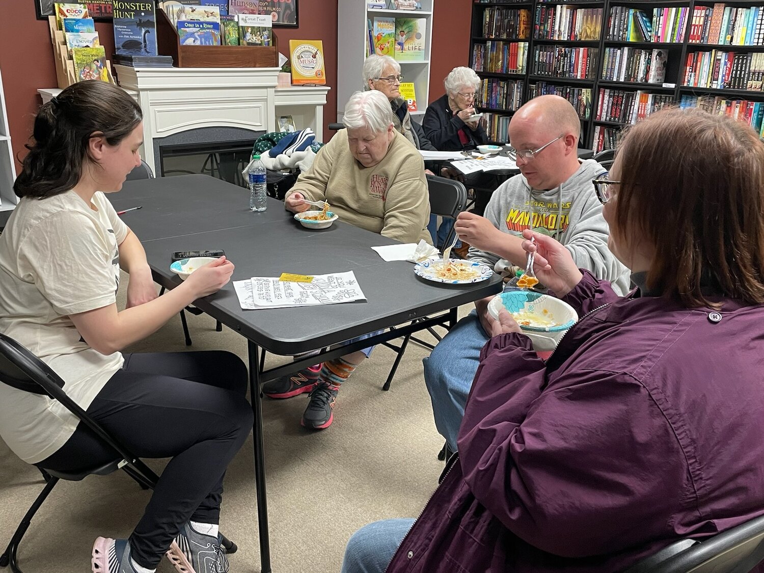 Julie Whittemore, left, owner of Keaton & Lloyd Bookshop, 238 W. Dominick St., tries some noodles with shop customers on Saturday.