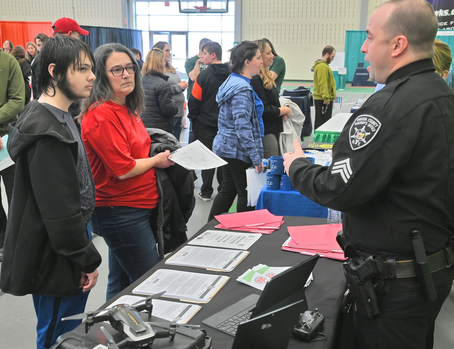 Oneida County Correction Division Sgt. Curtis Morgan, right, talks with Oneida High School student Connor Simms, left, and his mom, Michelle Simms, Tuesday, March 21, at the Exploring Careers in the Mohawk Valley event at Mohawk Valley Community College in Utica.