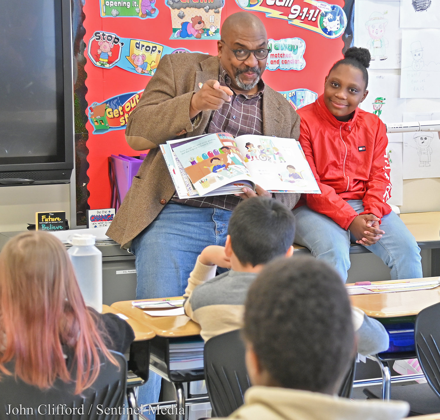 Dr. Mark Montgomery of SUNY Polytechnic and student Ka'Niyah Buchanan, sitting next to him, take a moment to acknowledge the camera as he read to the 4th grade class of Kelly Keller Friday morning at Kernan Elementary School.