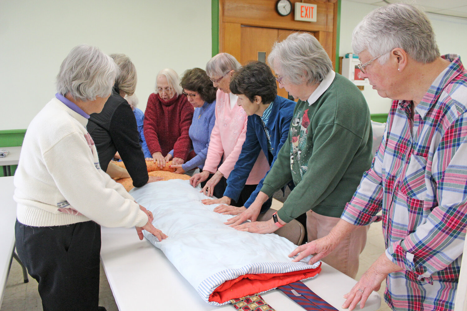 Members of My Brothers’ Keeper quilt group pray before tying up a sleeping bag at Dryden United Methodist Church, where they meet every Friday.