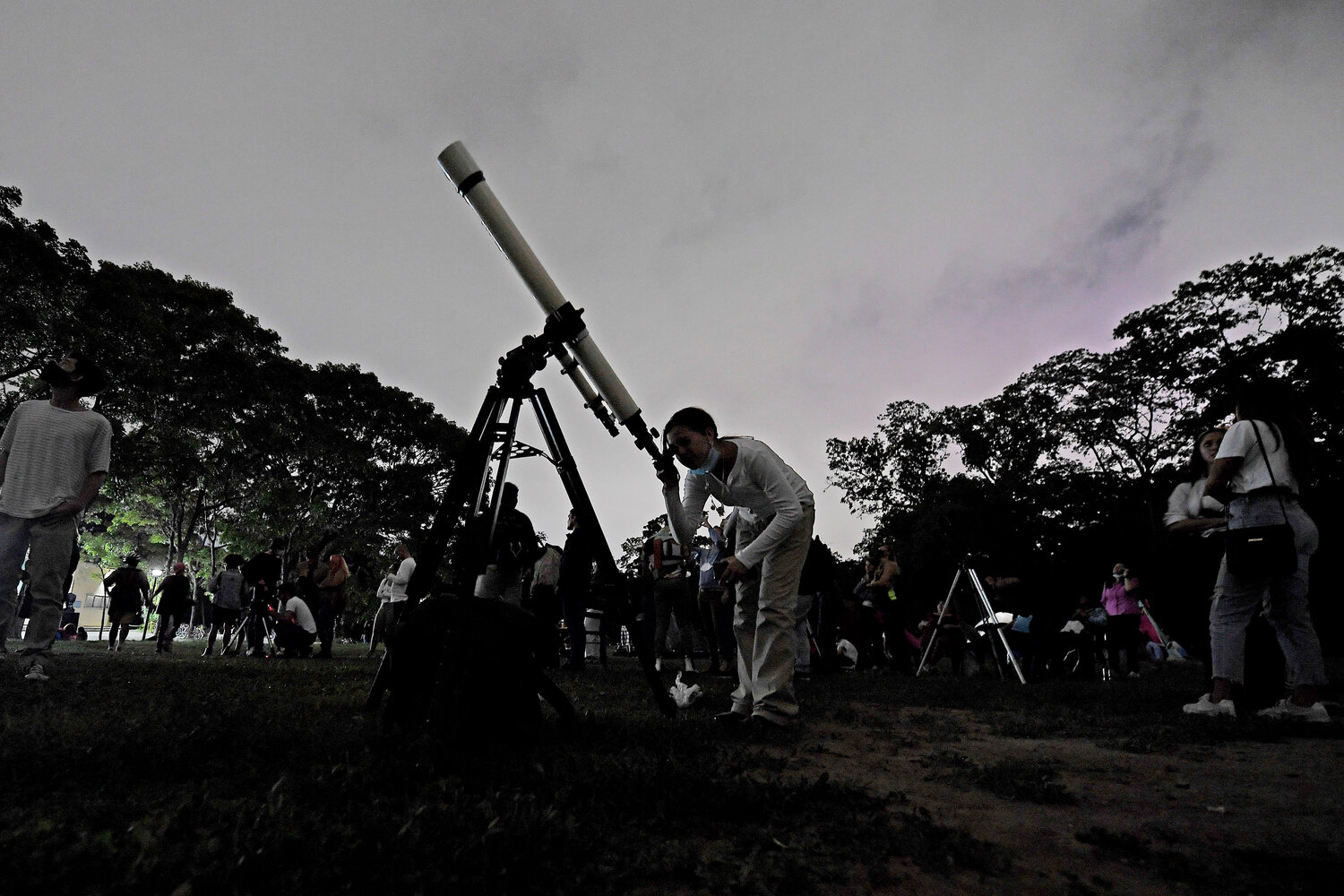 A girl looks at the moon through a telescope in Caracas, Venezuela, on Sunday, May 15, 2022. The best day to spot five planets, Mercury, Jupiter, Venus, Uranus and Mars, lined up in the night sky is Tuesday, March 28, right after sunset. The five-planet array will be visible from anywhere on Earth, as long as you have clear skies.