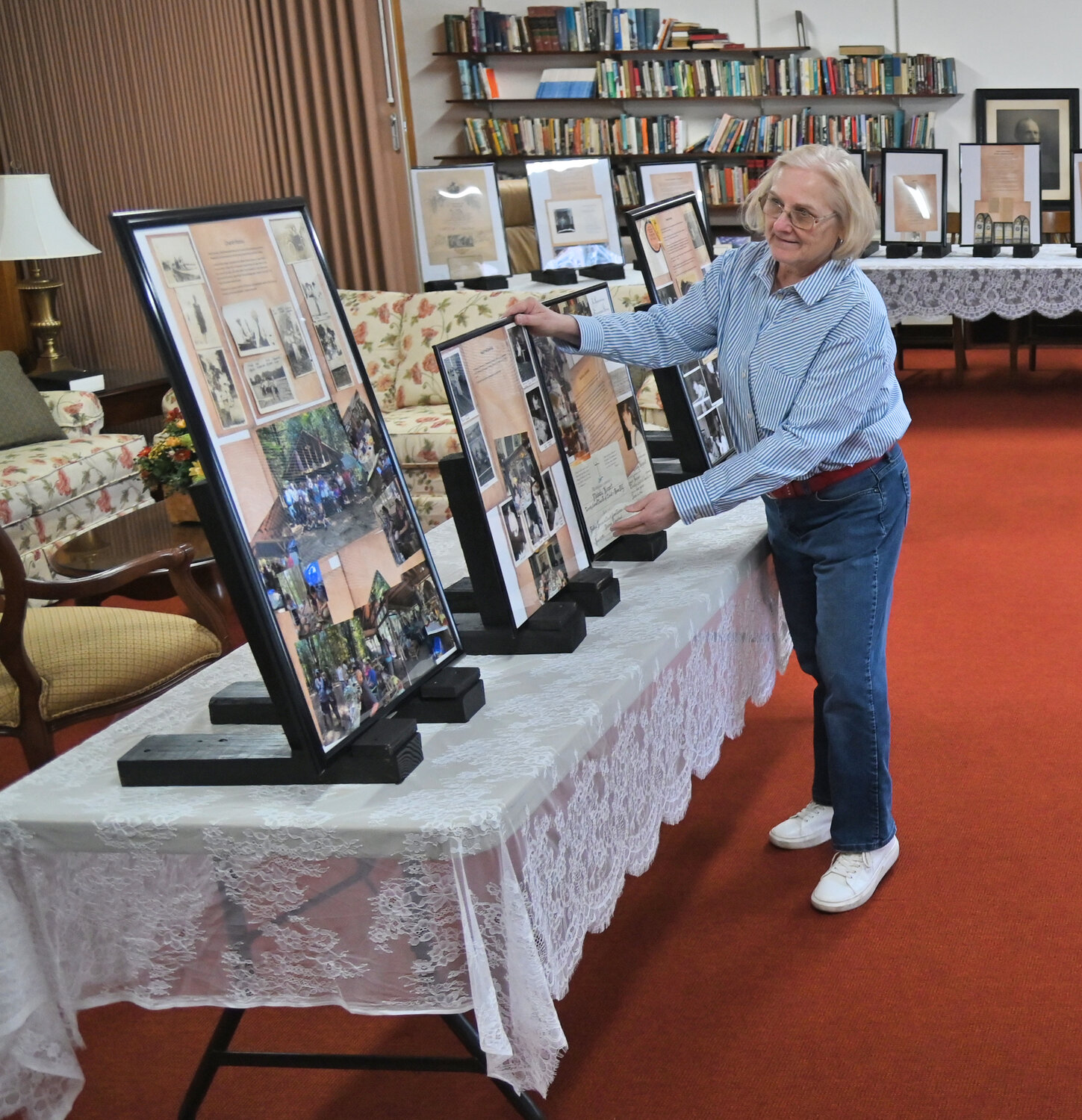 Trinity Church activities director and historian Melody Milewski straightens some framed history boards that are on display in the church lounge for its 175th anniversary celebration in April. Milewski collected and framed all the old photos and documents, including confirmation certificates in both English and German.