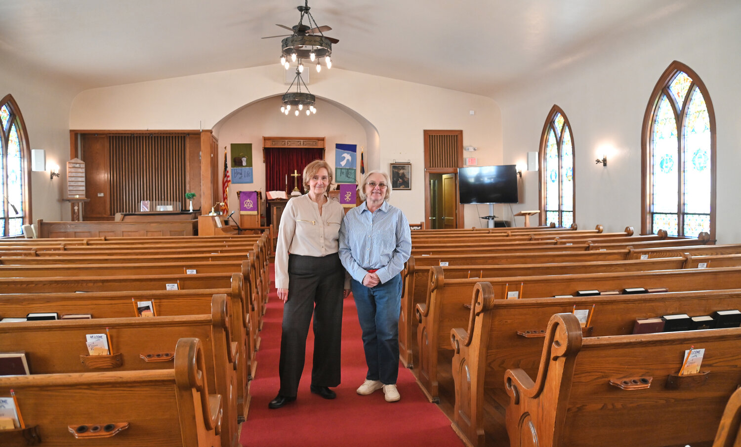 The Rev. Karen Marshall and Melody Milewski, activities director and historian, stand in the main aisle of Trinity Church, 215 W. Court St., Rome.