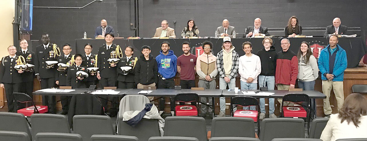 Navy Junior ROTC cadets and varsity boys track team members pose March 28 with the Utica City School District Board of Education at their regular monthly meeting at Kernan Elementary School in Utica.
