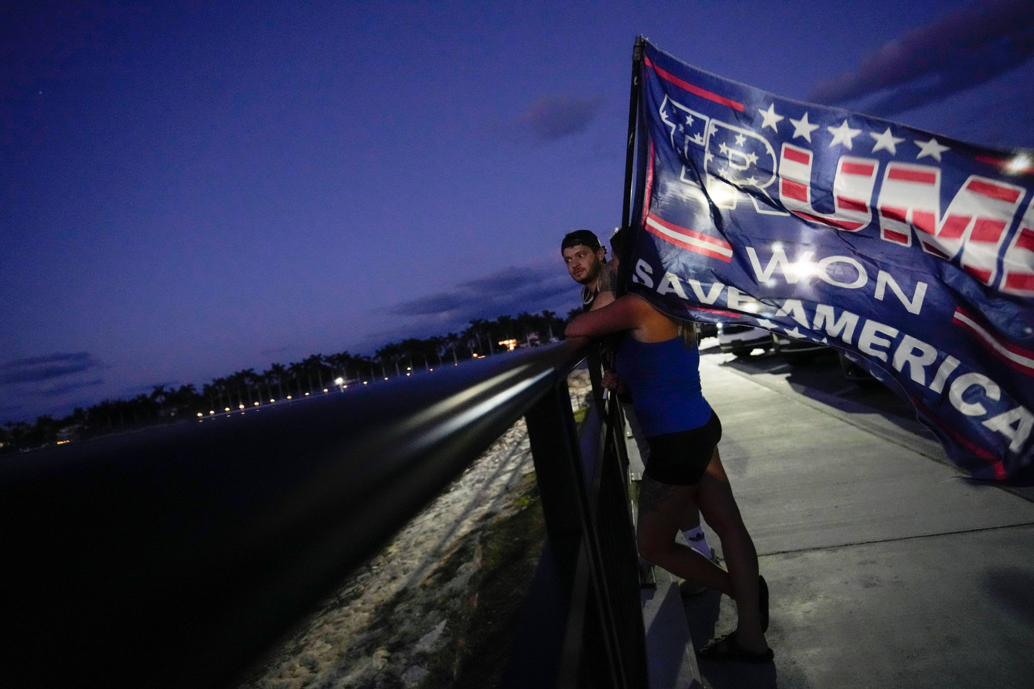 People hold a flag to show their support for former President Donald Trump following the news that Trump has been indicted by a Manhattan grand jury, Thursday, March 30, 2023, near Trump's Mar-a-Lago estate in Palm Beach, Fla.