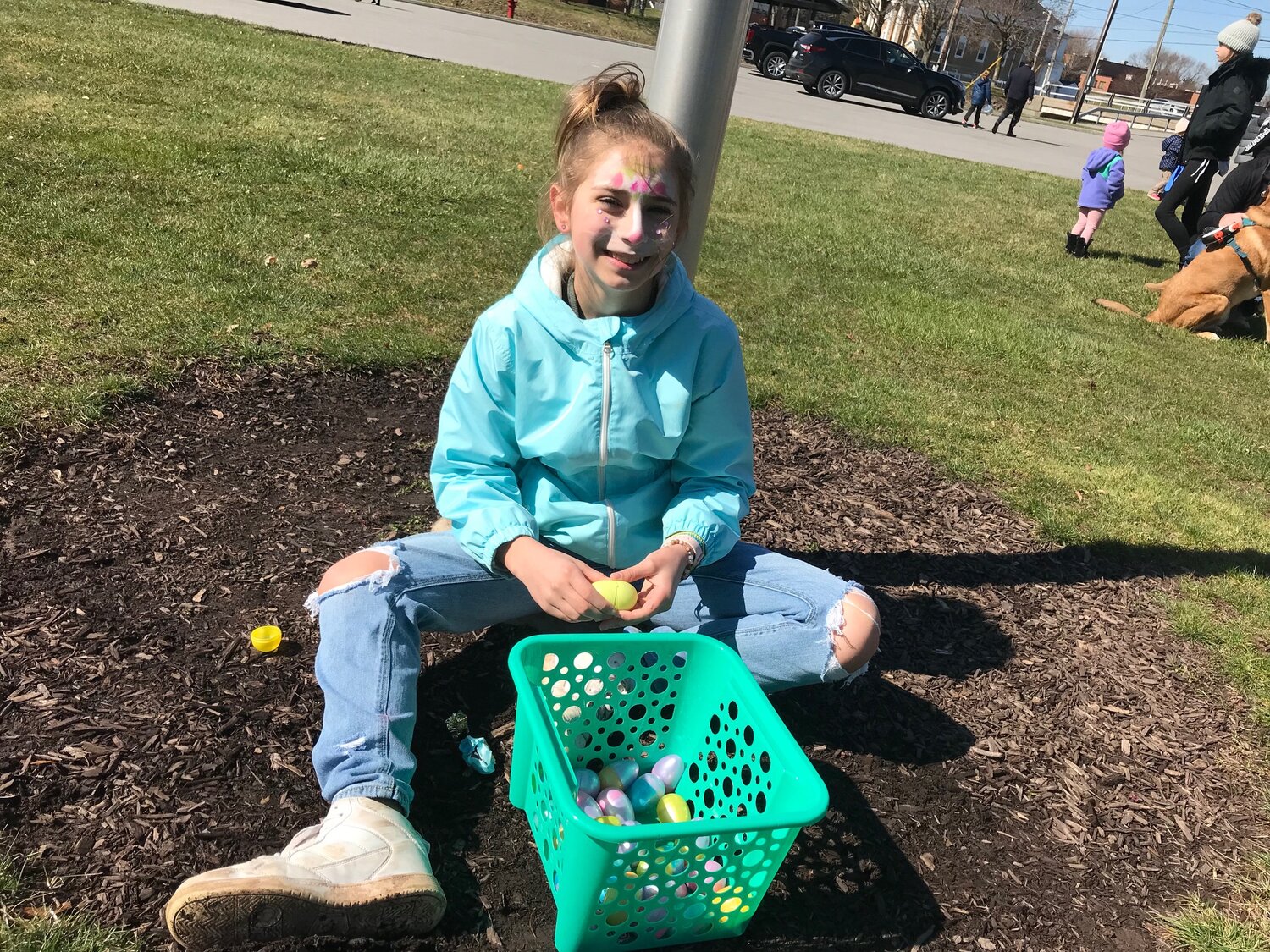 A facepainted Arianna Naegele checks her plastic eggs for the candy inside them Saturday, April 8 after the Easter Egg Hunt in Sherrill.