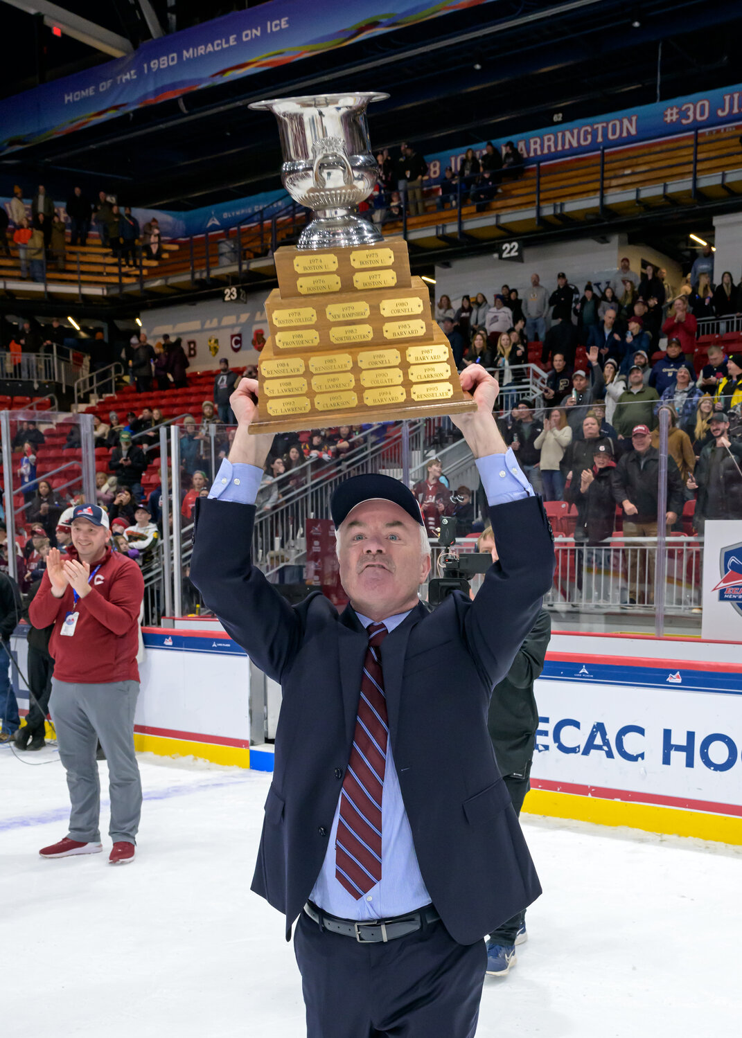 Colgate men’s hockey coach Don Vaughan hoists the Whitelaw Cup after the Raiders won the ECAC Hockey tournament with a win over No. 6 Harvard this season. The coach is retiring after 30 years leading the program.