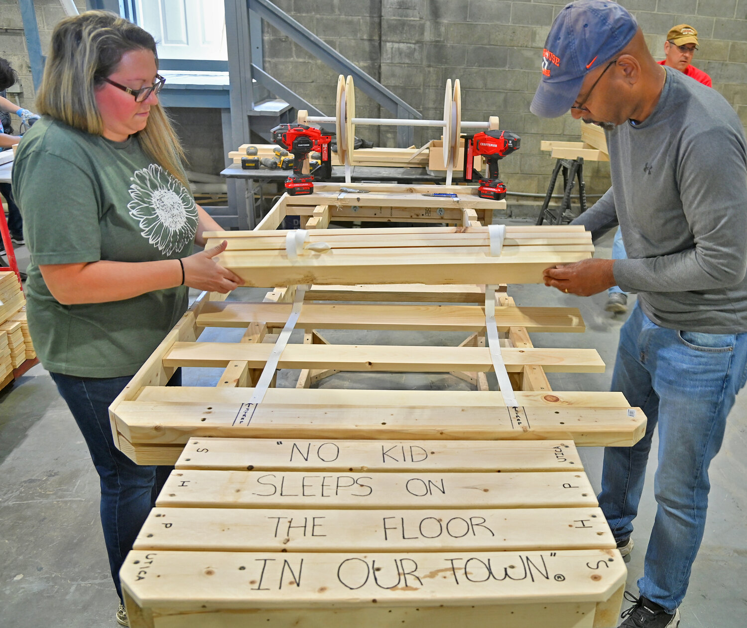 MAKING A DIFFERENCE ONE BED AT A TIME — Laura Davis, left, and Jerel Robertson roll up bed slats after installing mesh tape to keep them together during the Sleep in Heavenly Peace Mega Build on Friday afternoon in Yorkville. Volunteers with the local chapter of the non-profit organization are seeking to make 300 beds this weekend for local youngsters who currently don’t have a bed to sleep on. See story, page 2.