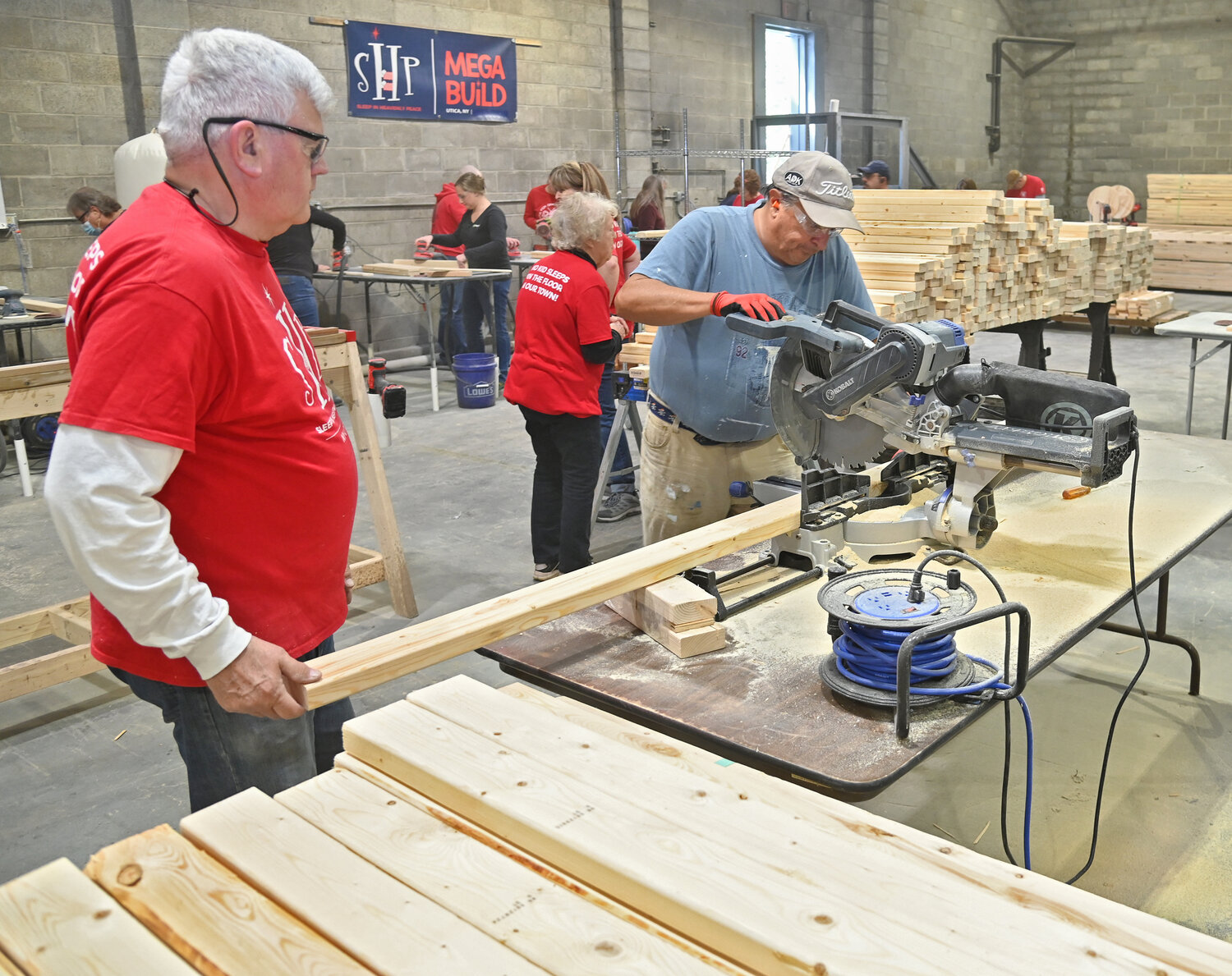 Larry Russell and Steve Johns cut wood for headboards during the Sleep in Heavenly Peace Mega Build II event in Yorkville on Friday afternoon.