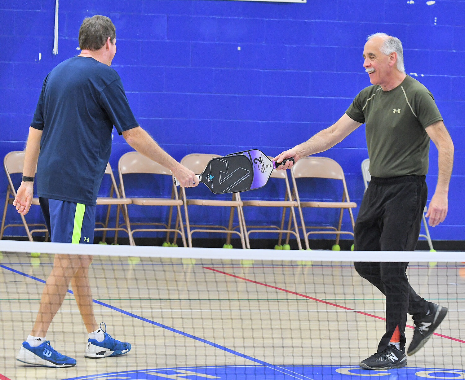 Pickle ball partners Jamie King and David Meislin clink paddles after scoring a point Thursday evening at the Jewish Community Center.