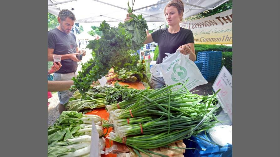 A vendor at the Clinton Farmers Market bags up kale for a customer in this 2018 file photo. Organizers are gearing up for another year with plans for this year’s market to open on June 1.