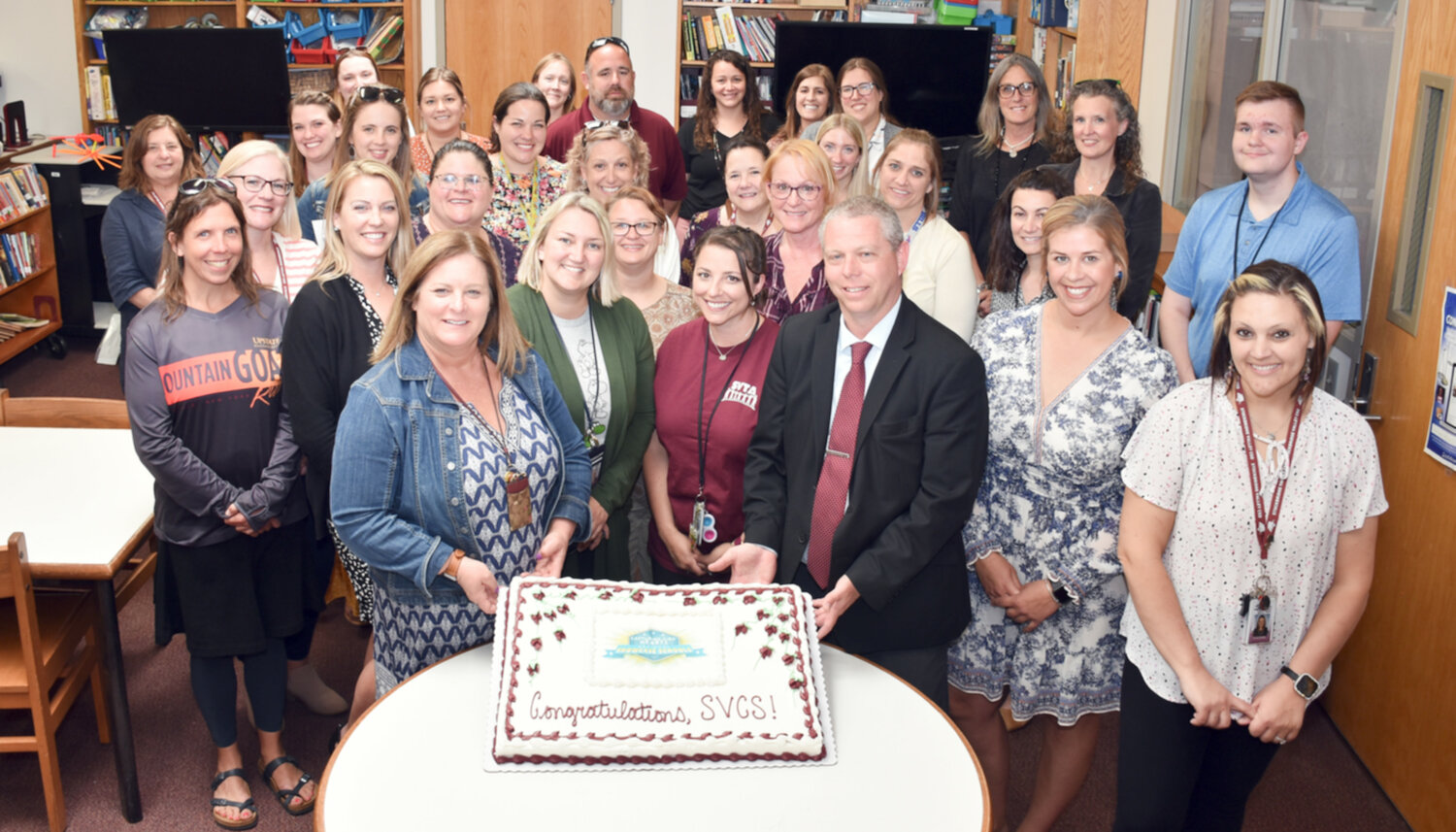 Stockbridge Valley Central School District Superintendent Corey Graves, front right, and Principal Julie Suber, front left, hold corners of a cake along with their elementary school staff. The school was the only district in the state chosen as a National Showcase School for the Capturing Kids’ Hearts framework.
