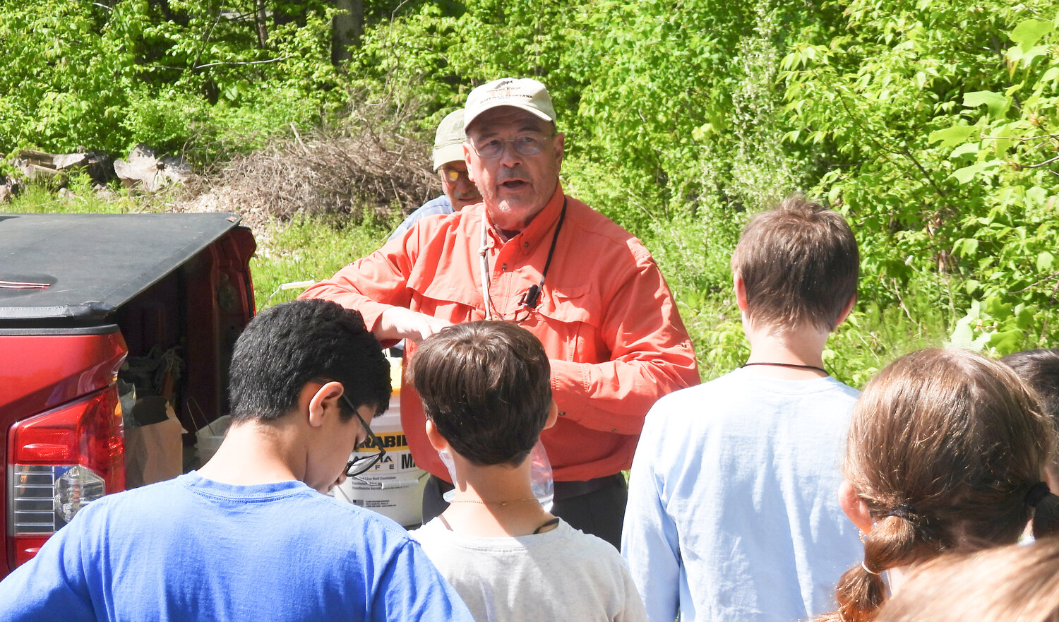 Students gather to listen to Gary Bartell, a volunteer with Trout in the Classroom, near Sconondoa Creek on Thursday, getting another lesson before the release.